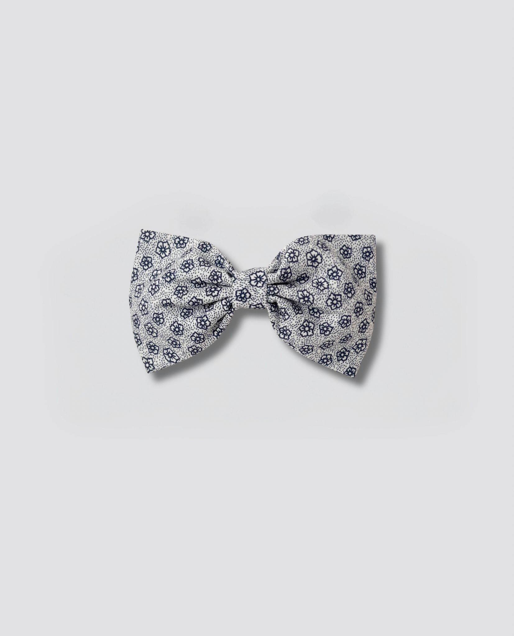 Small vintage-inspired bow clip featuring a delicate floral pattern in soft navy on natural organic cotton, perfect for adding a charming touch to children's outfits.