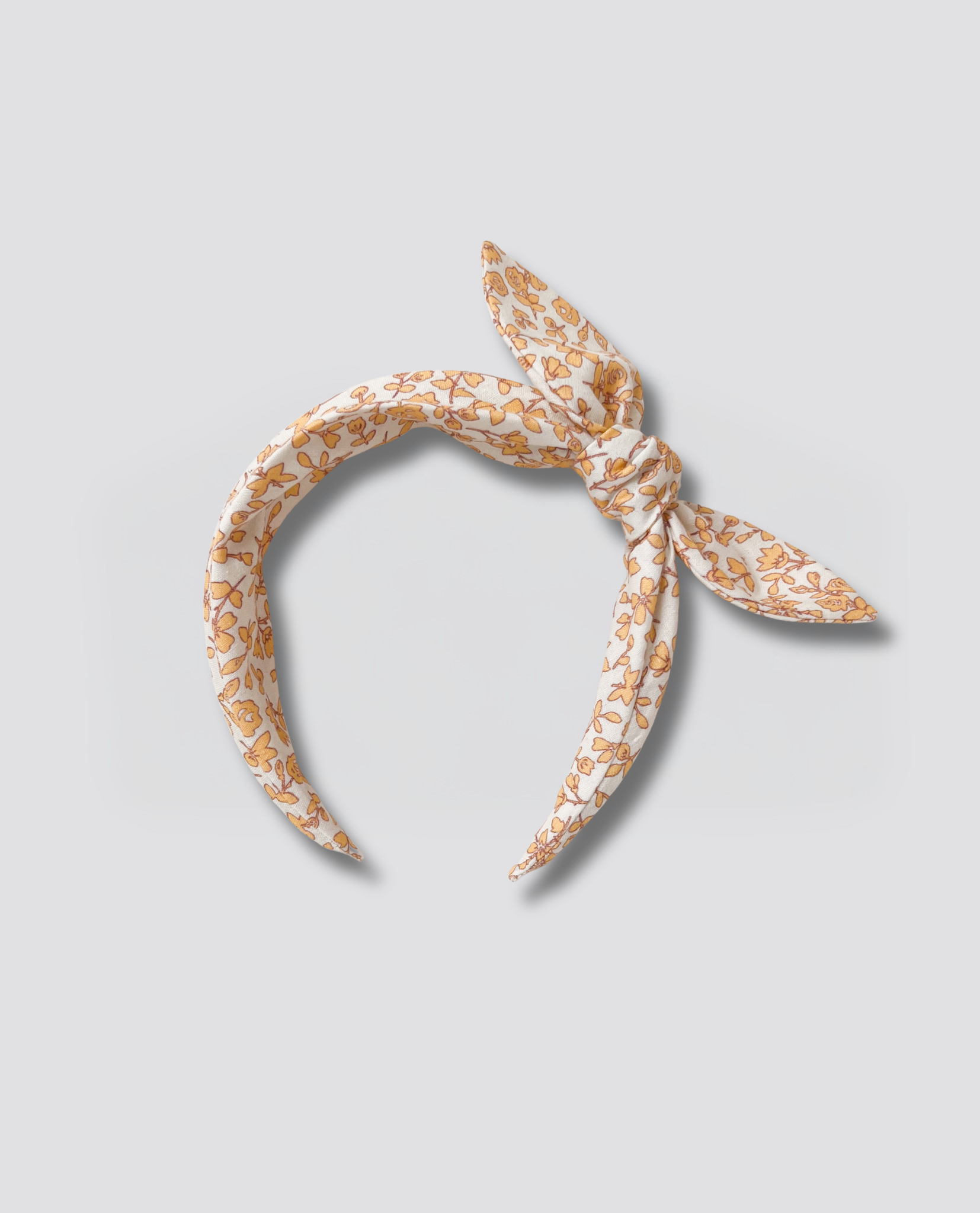 Wide children's hairband with a vintage-inspired floral print in soft orange tones, made from organic cotton for a natural, sustainable accessory.