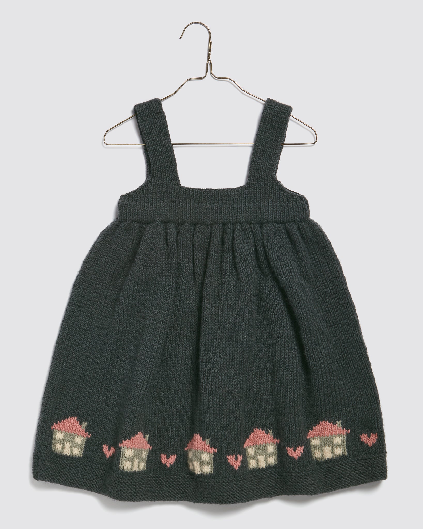 Hand-knitted navy pinafore dress for kids made from soft merino wool, featuring a charming vintage cottage pattern in beige and pink, perfect for sustainable, ethical children's clothing.