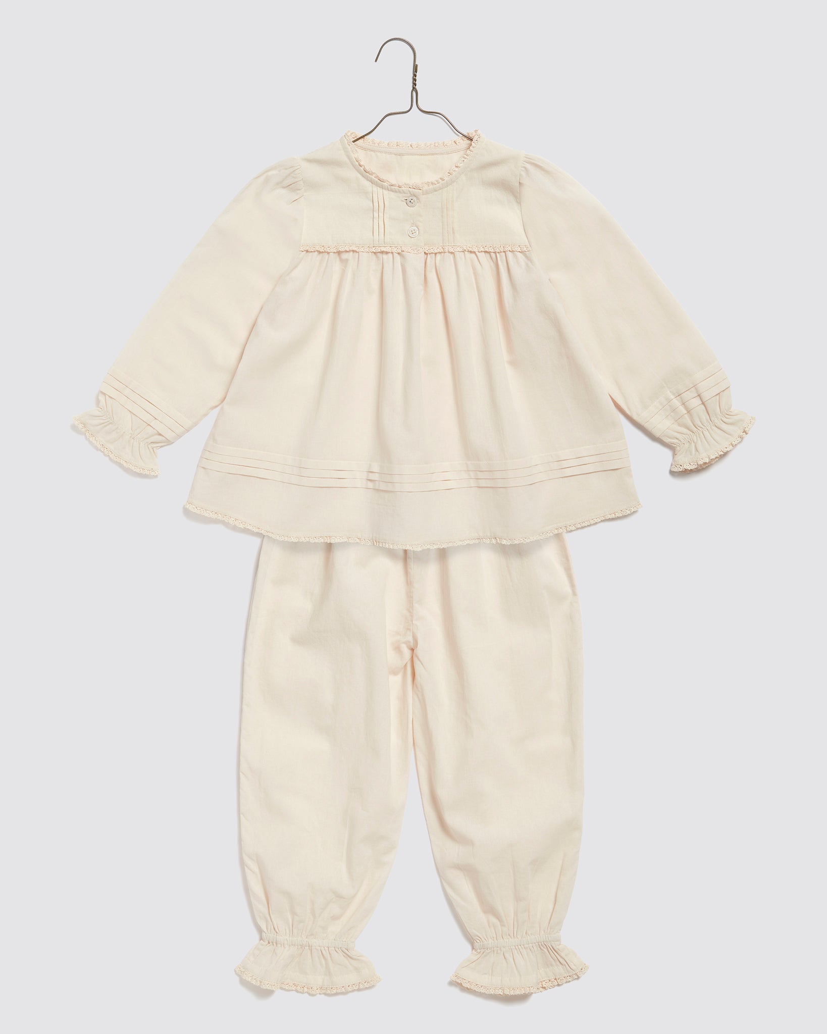 Soft organic cotton pyjamas for kids in a delicate dew color, featuring vintage-inspired details and gentle ruffles for traditional, sustainable children's clothing.