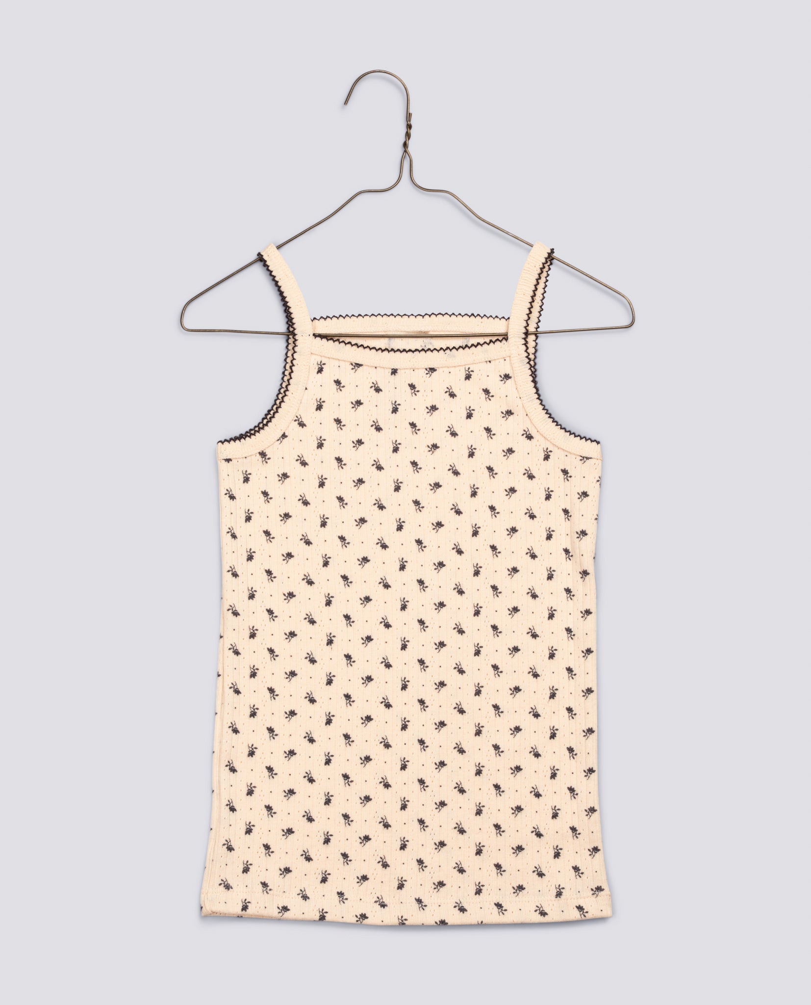 Light cream sleeveless vest with delicate small blue floral pattern and contrasting trim, made from soft organic cotton for vintage-inspired children's wear.