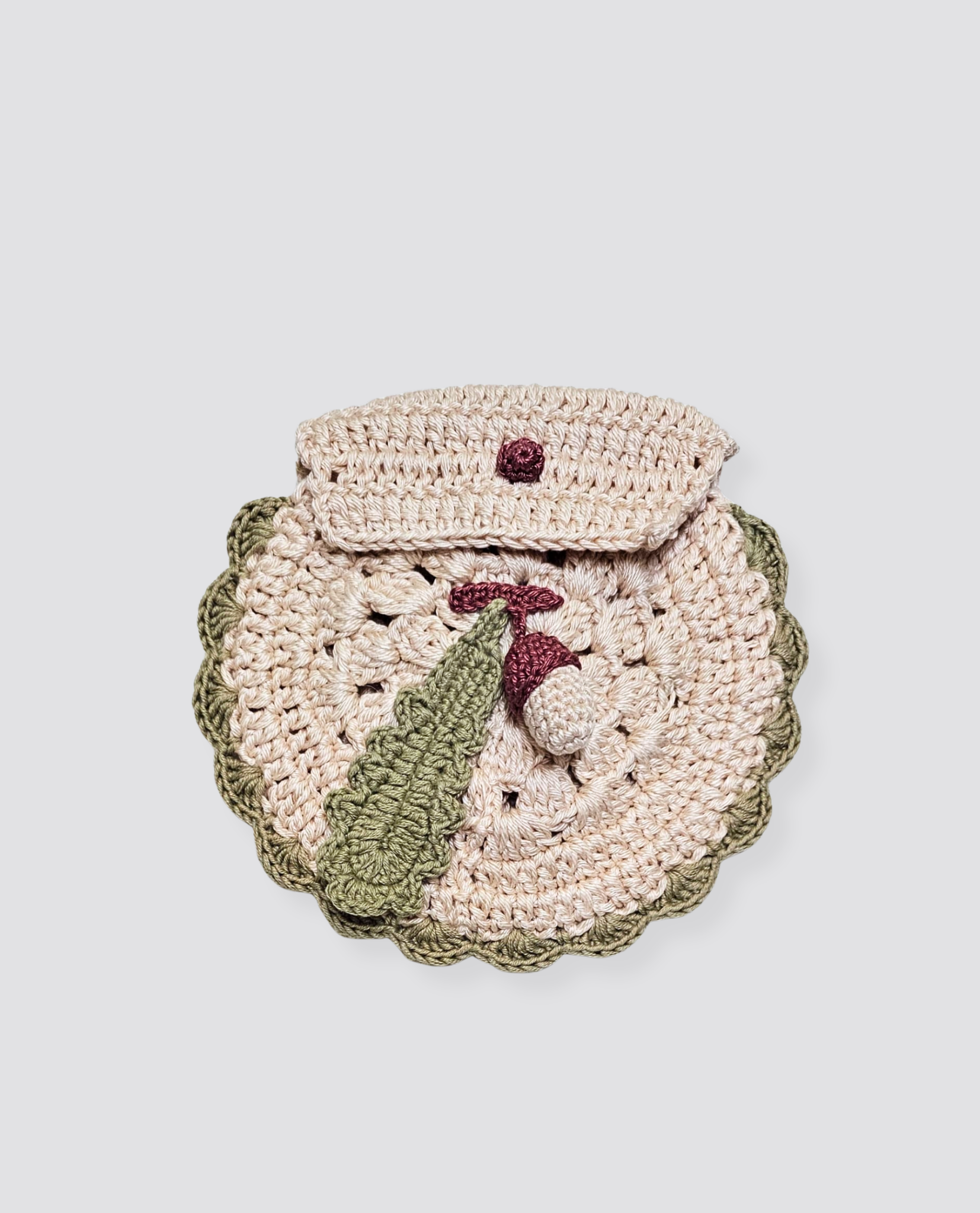 Handmade crochet acorn-shaped purse in natural and earthy tones, featuring a delicate green leaf detail, crafted with sustainable materials for children’s accessories.