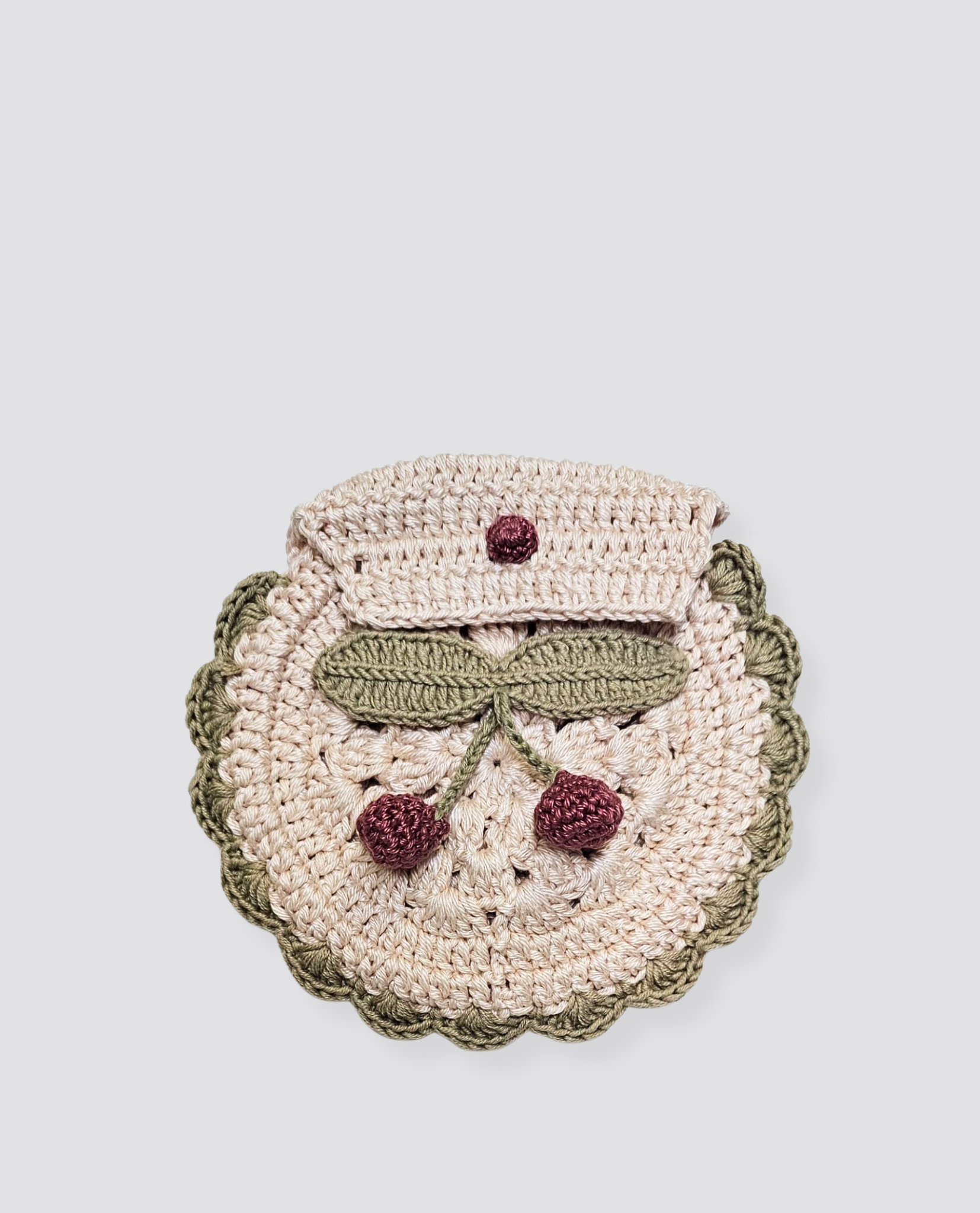 Round handmade crochet purse featuring a cherry design with green leaves and red cherries, crafted in natural cotton with a vintage, sustainable style.