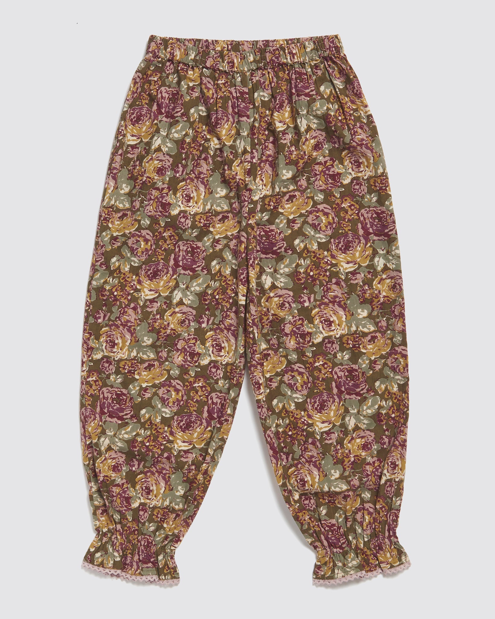 Children's vintage-style trousers in soft organic cotton with a warm floral pattern in muted tones, designed with elastic waist and gathered cuffs for comfort and style.