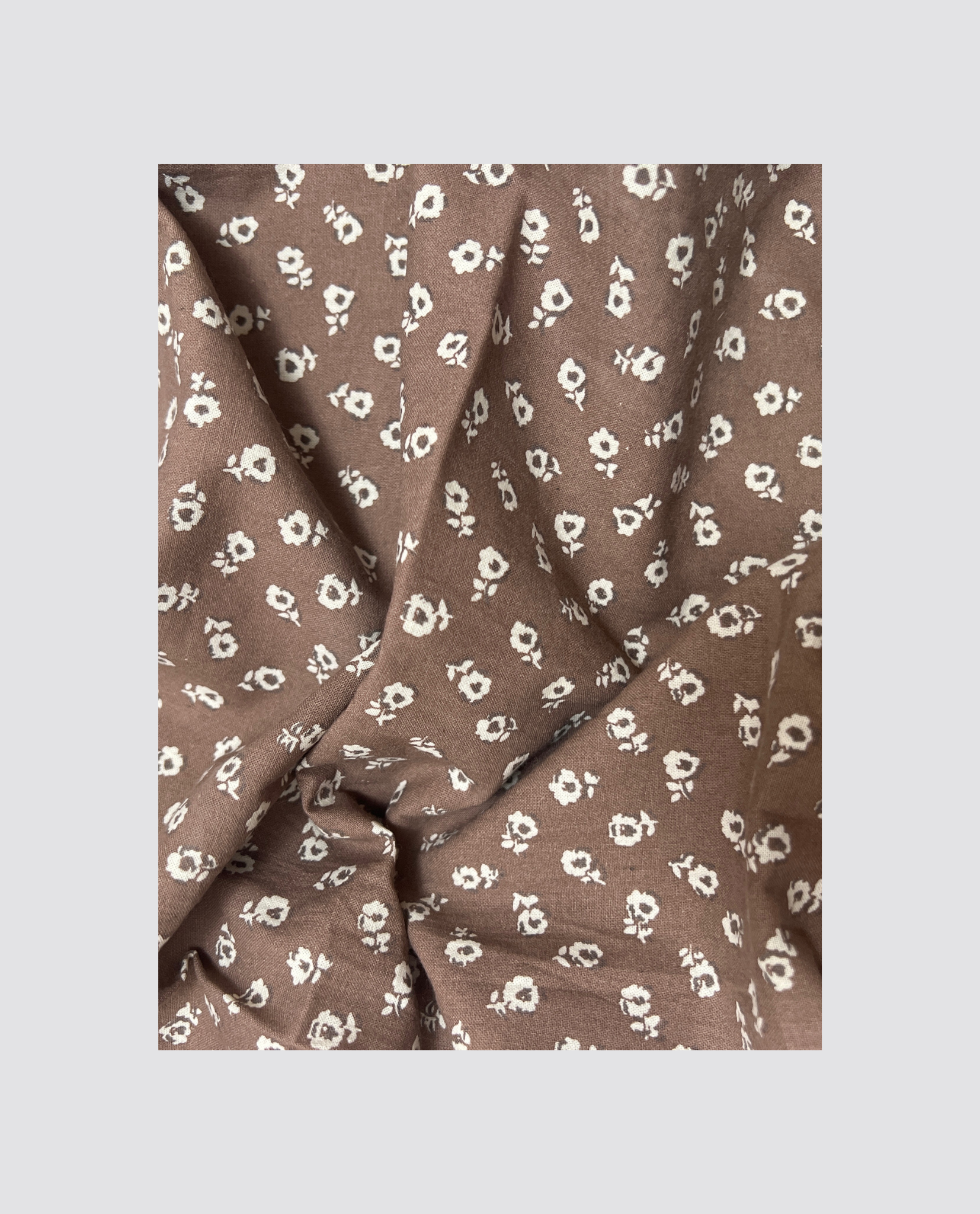 Soft brown organic cotton fabric with a delicate white floral pattern, perfect for creating vintage style children's clothing that is natural, sustainable, and ethically made.