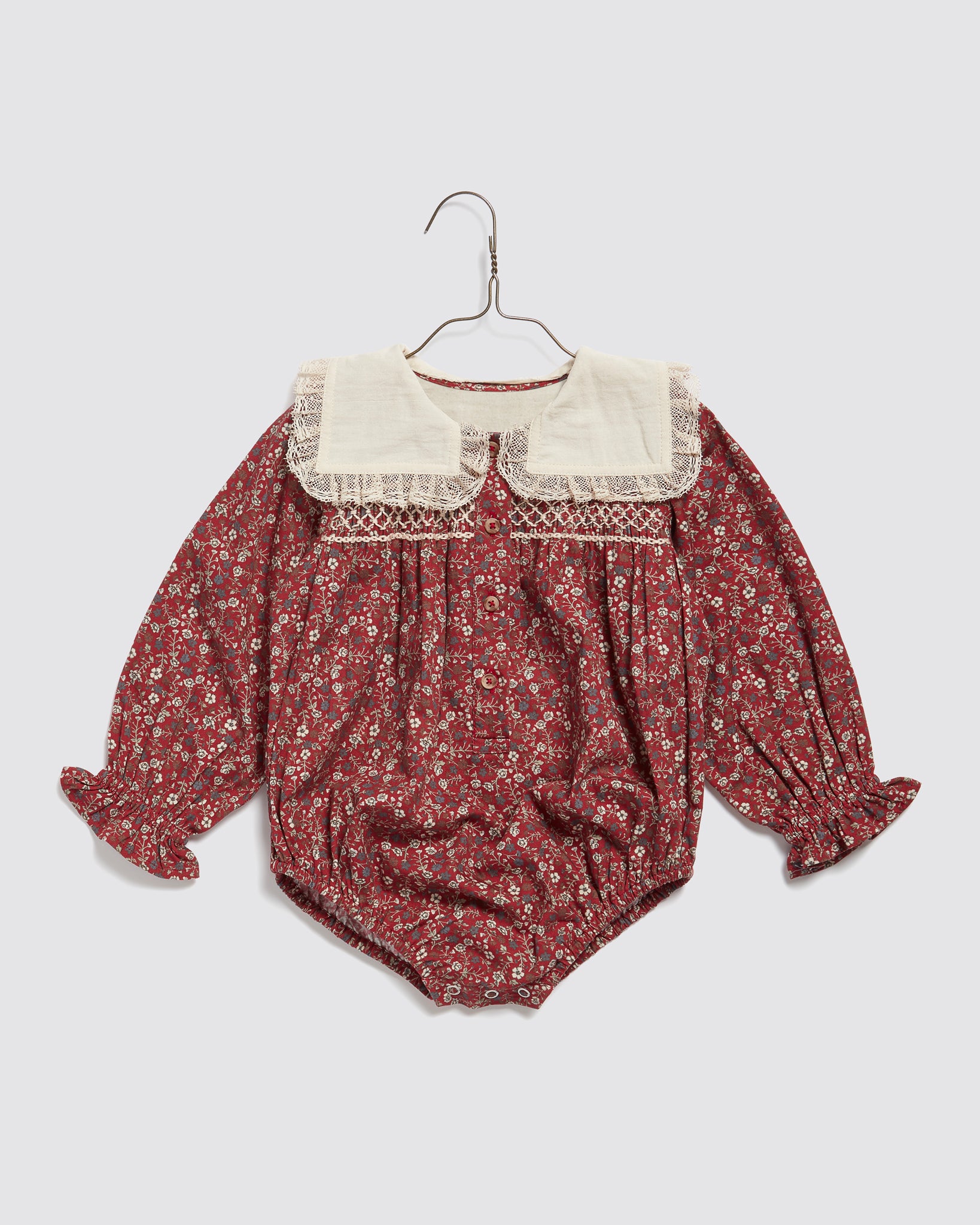 Vintage style baby romper with long sleeves in a clove floral print, featuring a large lace-trimmed collar made from natural organic cotton.