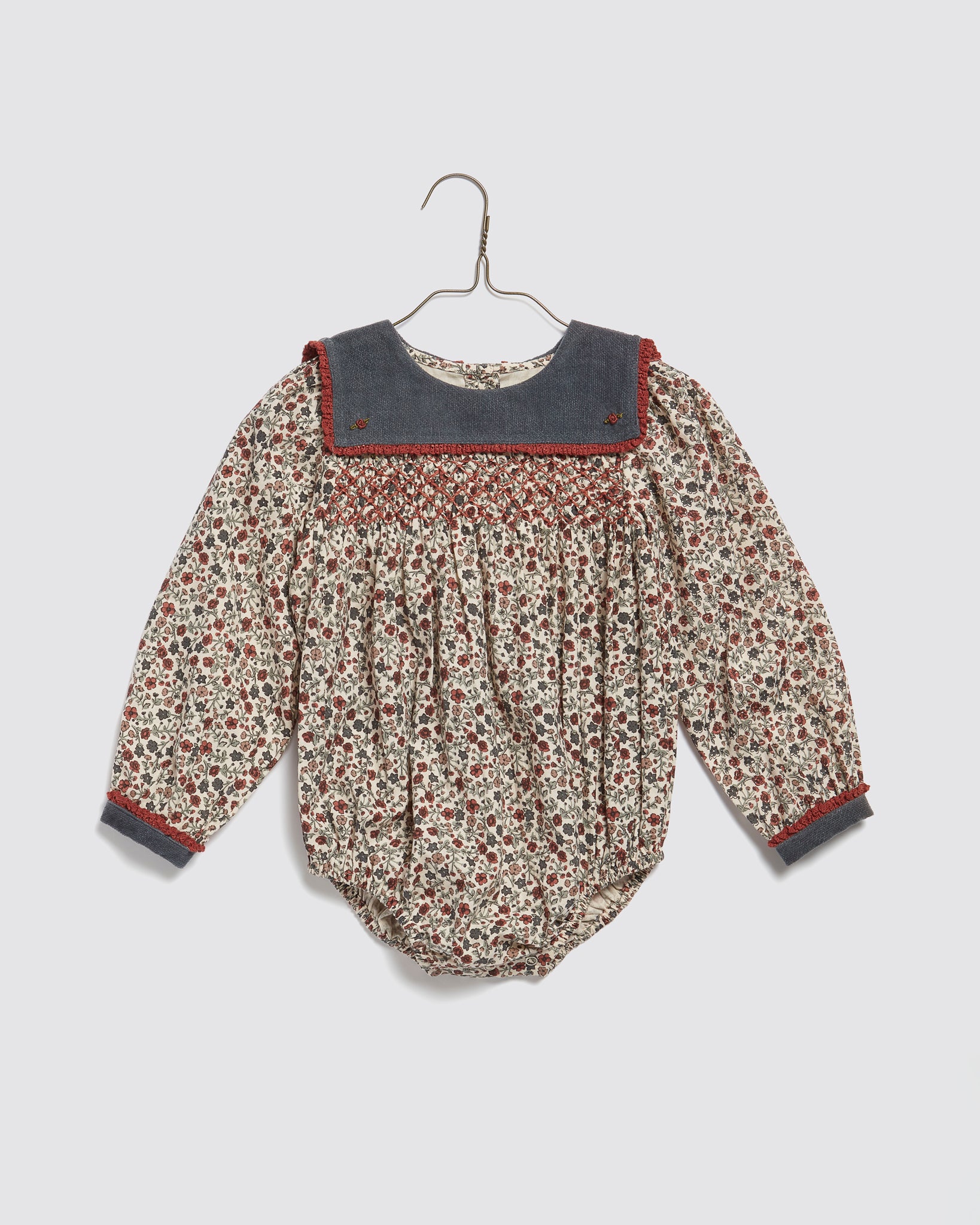 Vintage style organic cotton baby romper with a cottage floral pattern, featuring long sleeves and a contrasting collar, designed for sustainable children's clothing.