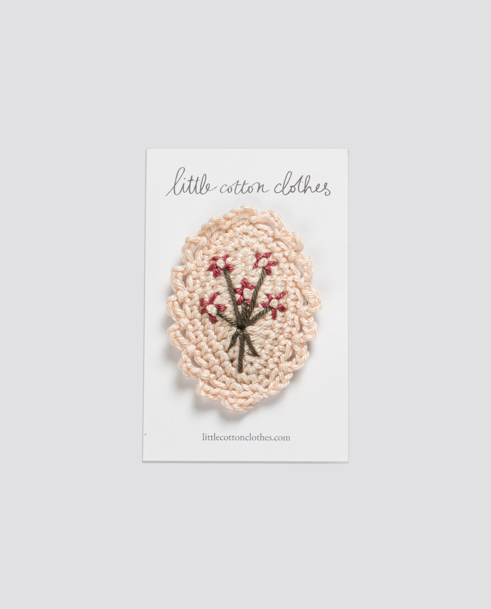 Cream-colored crocheted hair clip featuring a delicate bunch of tiny embroidered flowers, handmade with natural materials in a vintage style for children.