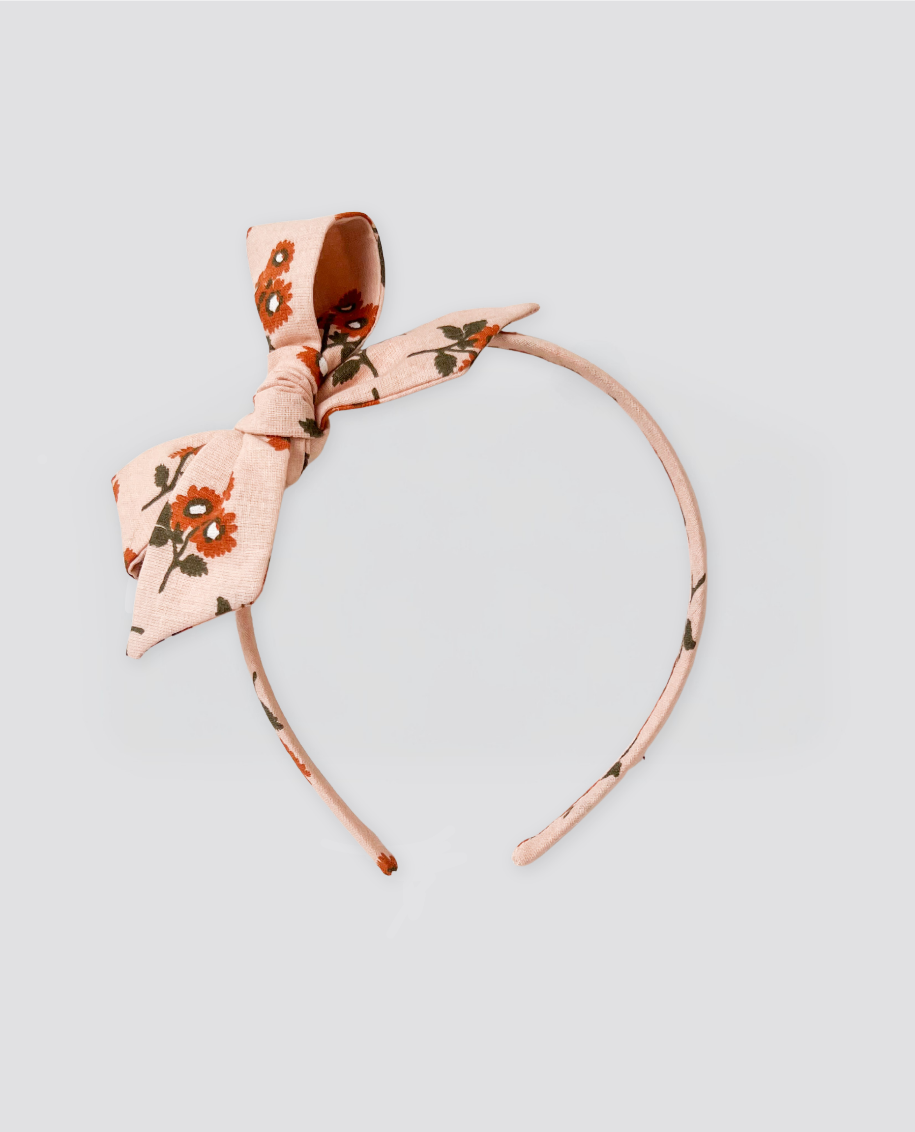 Soft pink retro-style girls’ headband with marigold floral print, made from natural cotton, perfect for vintage-inspired sustainable children’s clothing.