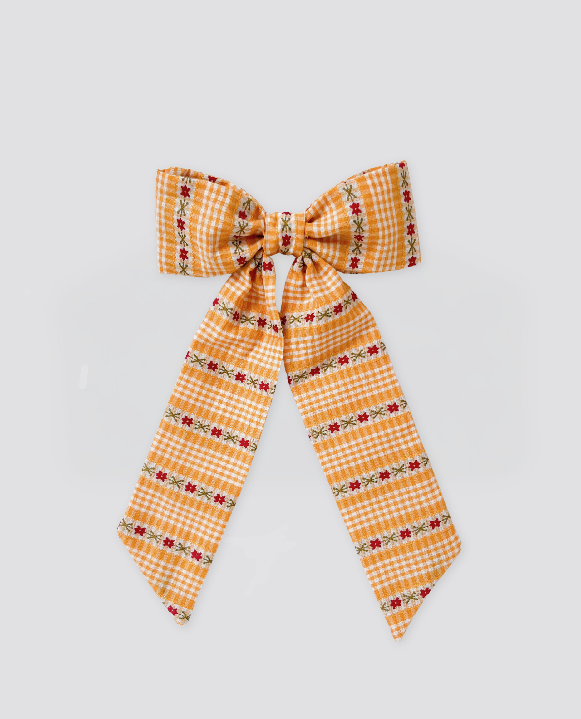 Yellow gingham bow clip with delicate floral embroidery, made from organic cotton, reflecting a vintage, natural style perfect for children's clothing.