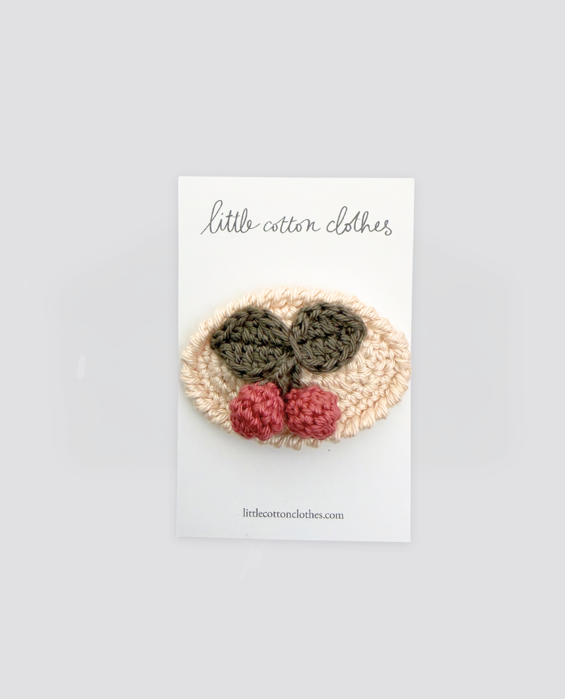 Handmade crochet hair clip with cherry design featuring natural colors, crafted for children’s vintage style and sustainable, organic clothing brands.
