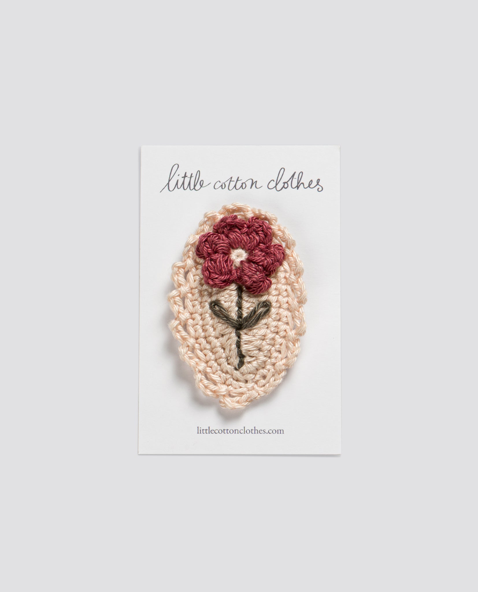 Handmade crochet hair clip with a vintage-style red dahlia flower on a natural organic cotton base, perfect for sustainable kids clothing accessories.