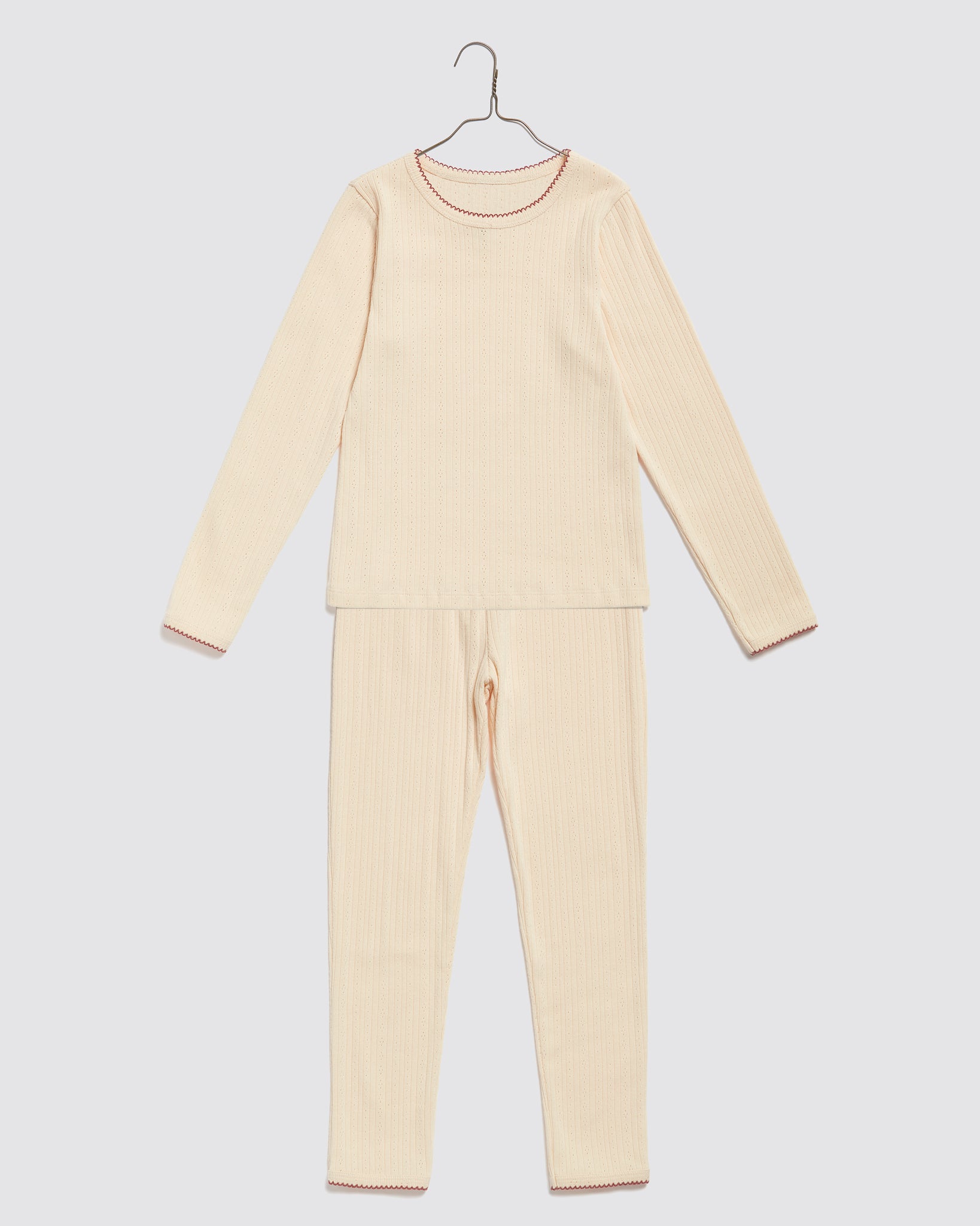 Soft buttermilk-colored ribbed pyjamas for children made from organic cotton, featuring delicate vintage-inspired edging for a natural and ethical sleepwear option.