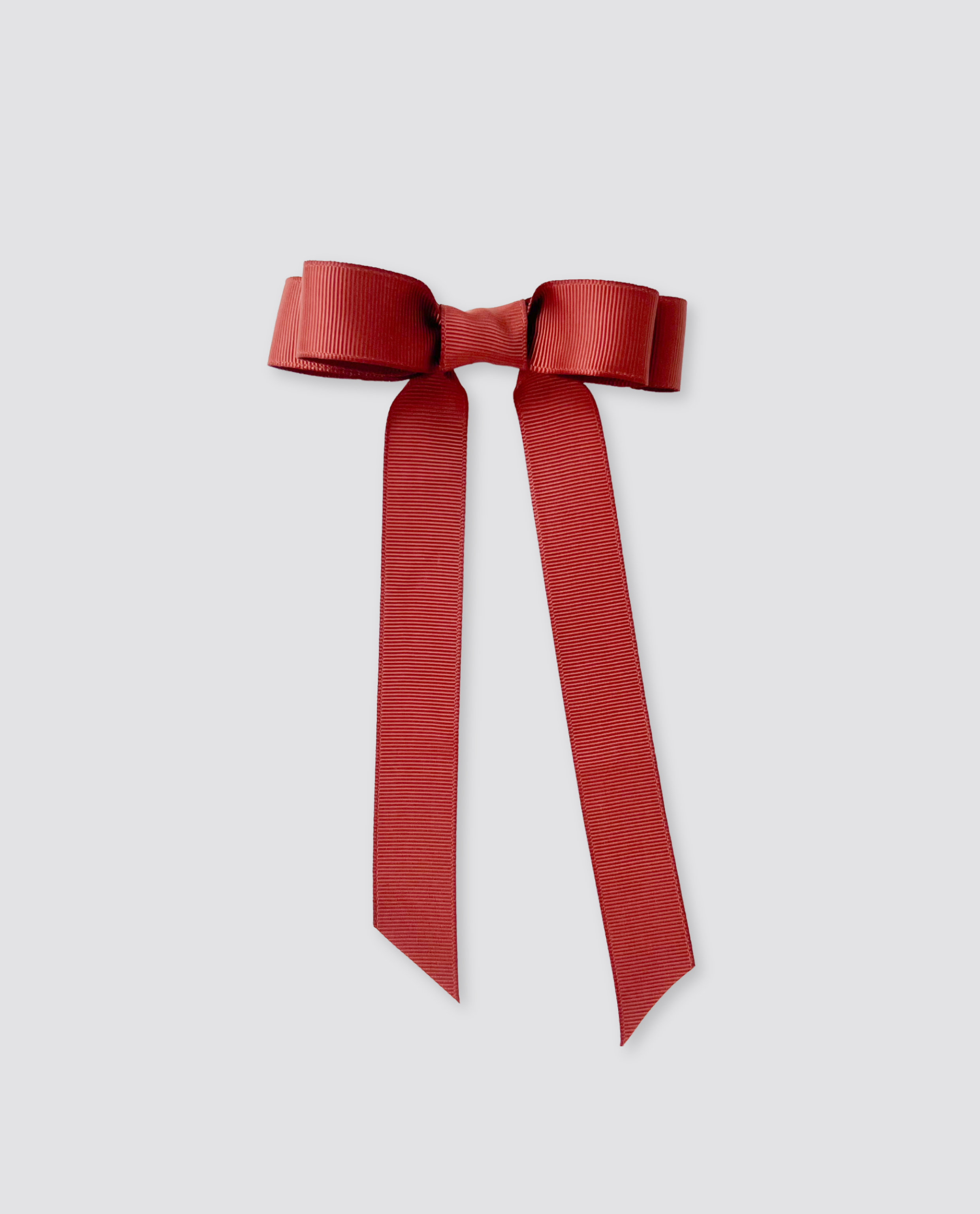 Deep red grosgrain ribbon bow with long tails, designed in a vintage style for children, crafted with organic materials and ethical principles.