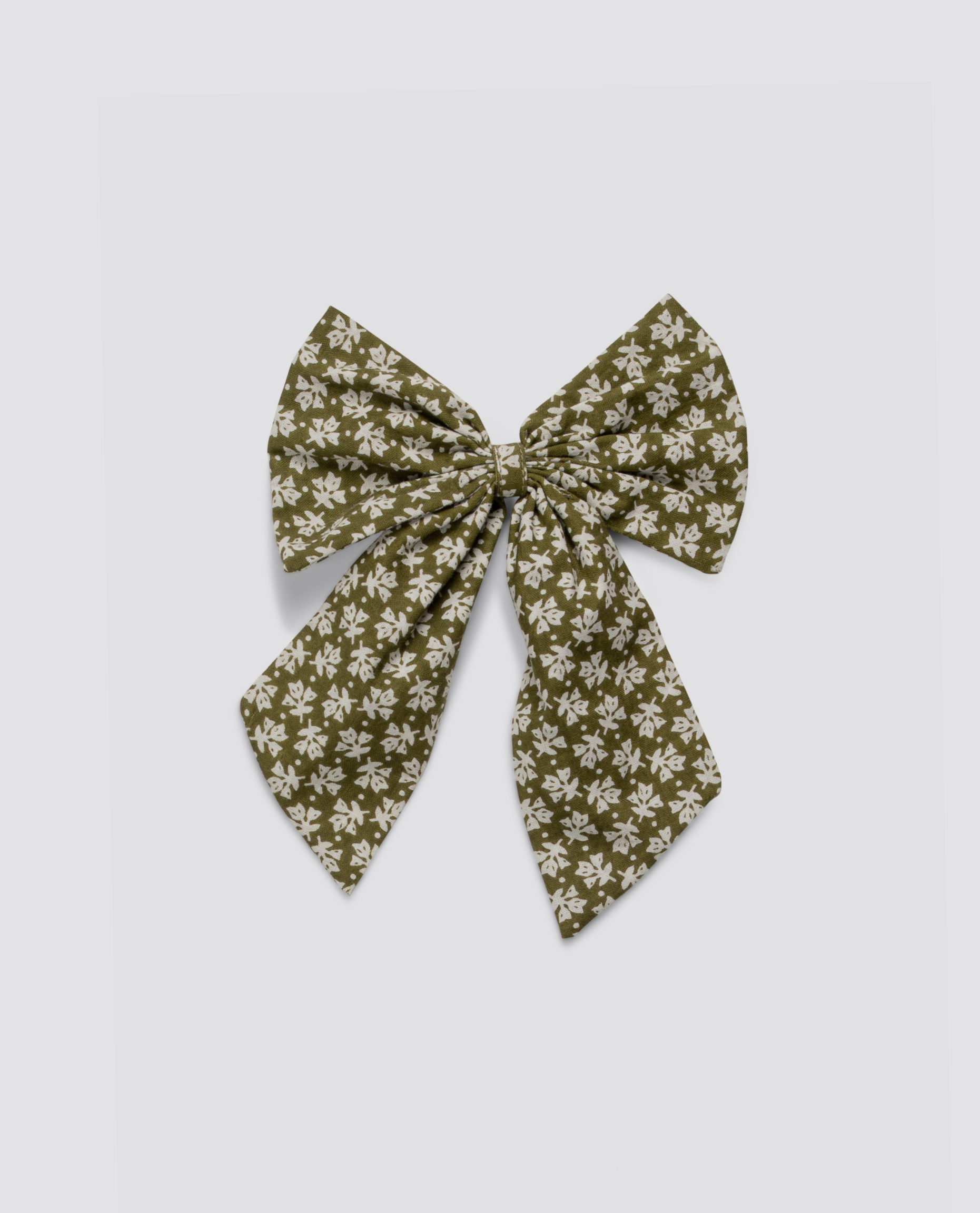 Green floral fabric bow with elastic, made from organic cotton, featuring a vintage-inspired delicate pattern, perfect for sustainable and ethical children's clothing.