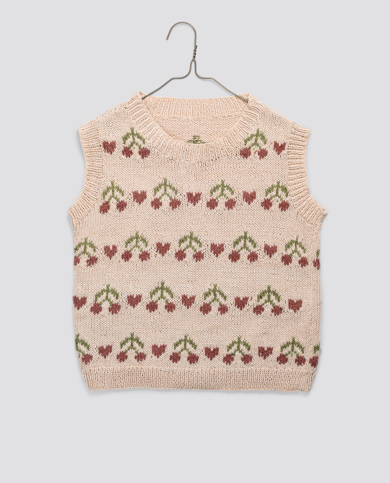 Hand-knitted children's vest in soft organic cotton with a vintage-inspired cherry pattern, showcasing natural materials and sustainable, ethical craftsmanship.