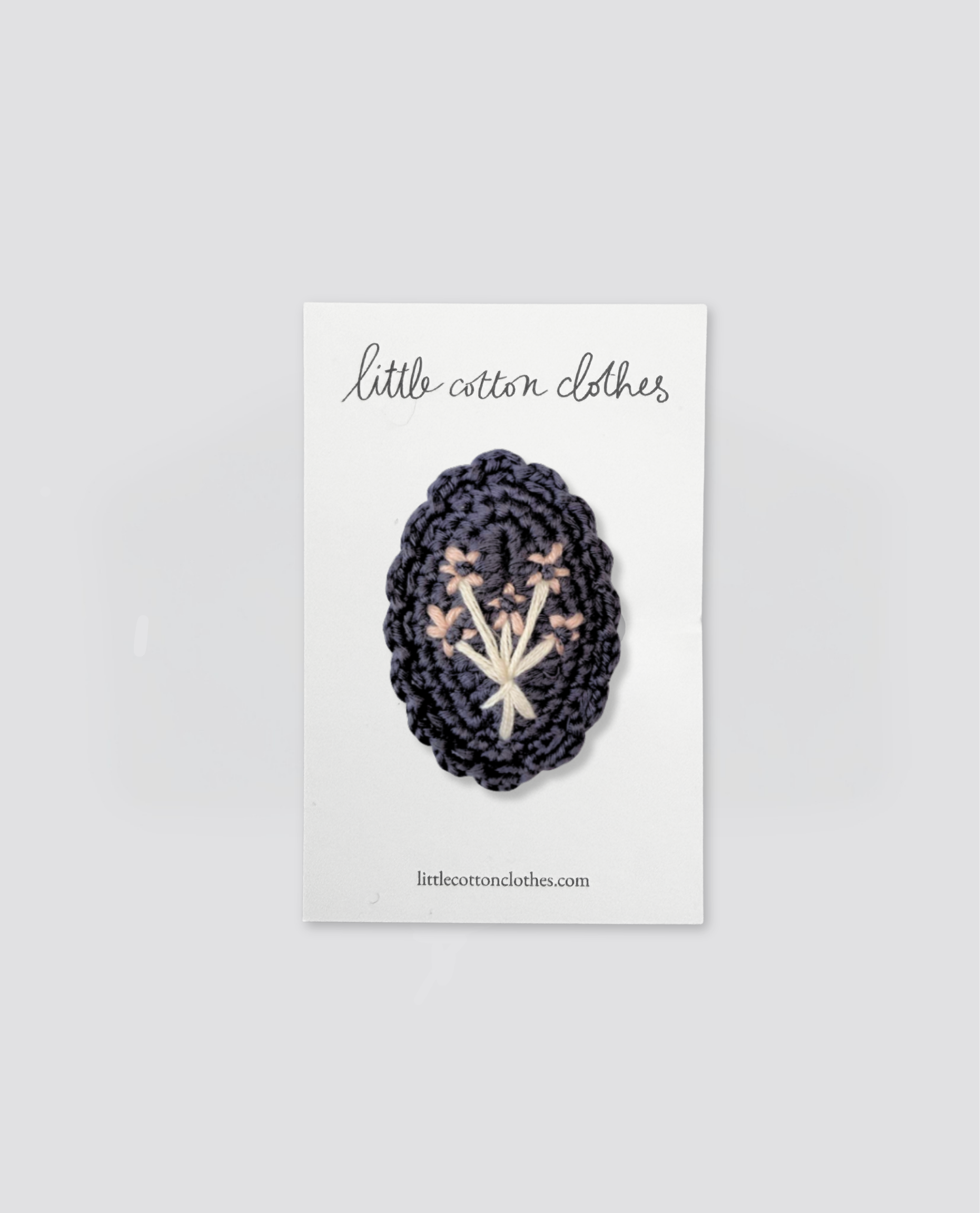 Blue crochet hair clip with embroidered flowers on a white card, showcasing a natural, vintage-inspired accessory for children's clothing from a slow, ethical brand.