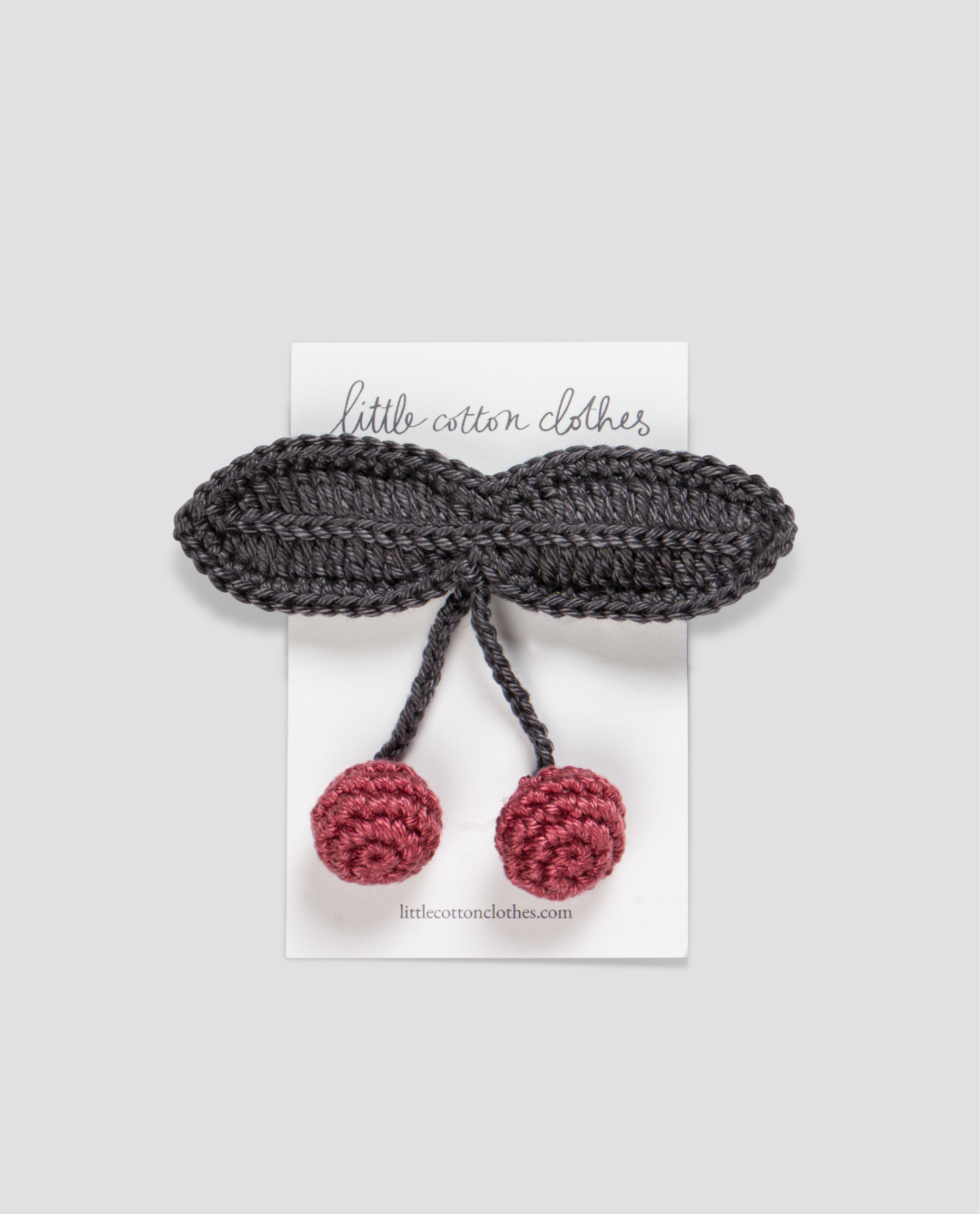 Handmade crochet hair clip featuring navy blue leaves and two red cherries, crafted from organic cotton for sustainable, vintage-inspired children's clothing.