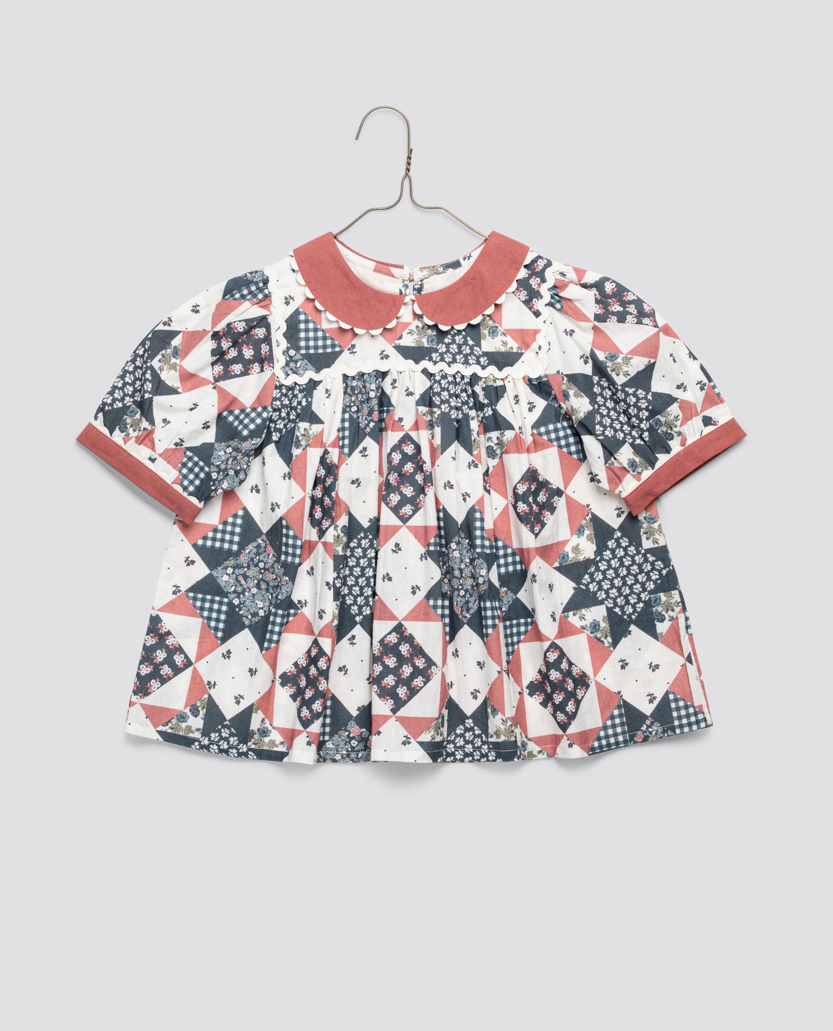 Vintage style girls blouse in organic cotton with a charming patchwork floral and geometric print, featuring a soft collar and short sleeves for a natural, ethical choice.