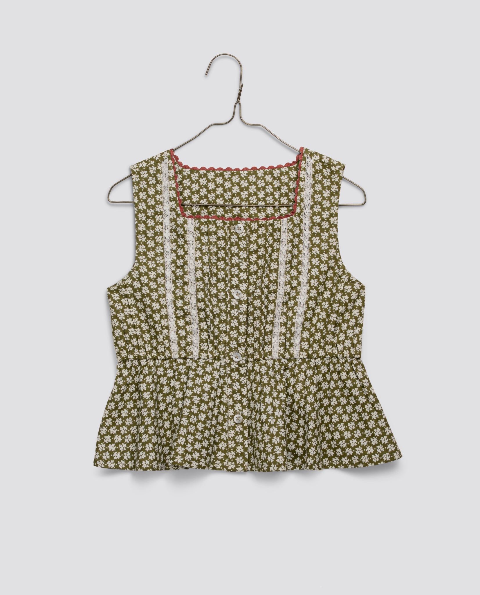Vintage style sleeveless girls blouse with a green floral pattern, featuring white lace trim and delicate button details, made from organic cotton for sustainable children's clothing.