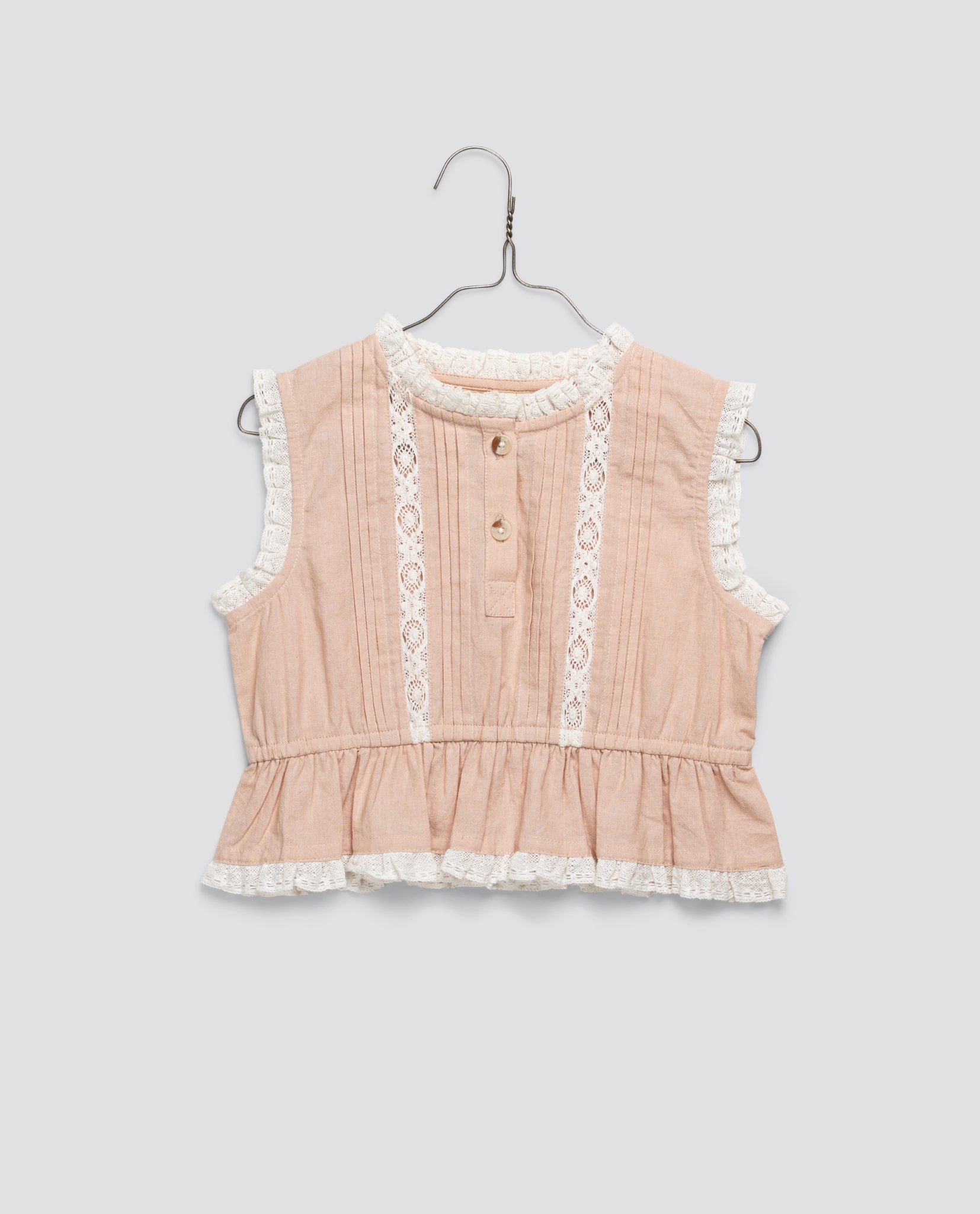 Sleeveless girls blouse in soft powder pink organic cotton with delicate white lace trim and wooden buttons, featuring a vintage-inspired design for sustainable children's clothing.