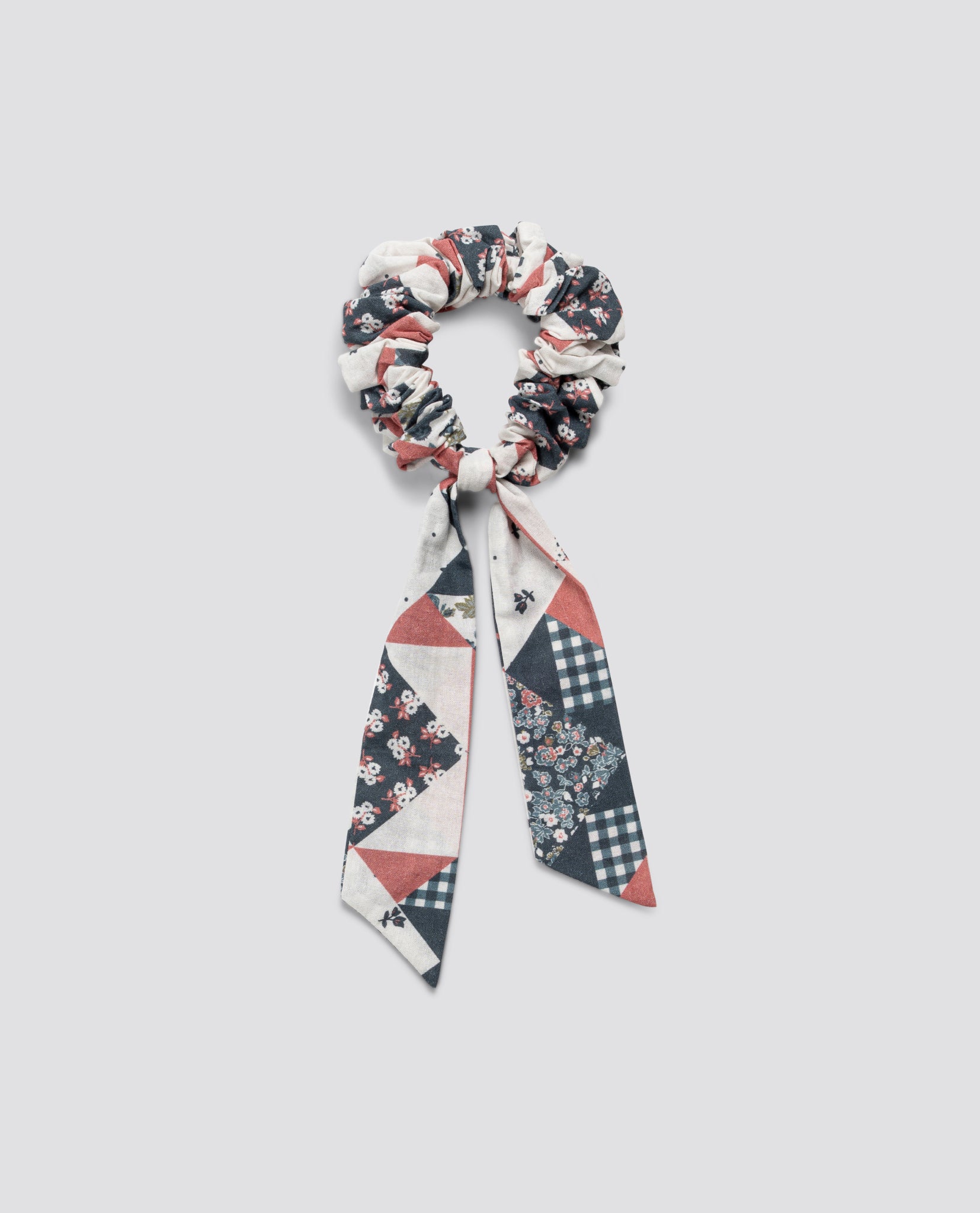 Scrunchie with long bow in patchwork floral pattern made from soft organic cotton, reflecting vintage-inspired, sustainable children's accessories.