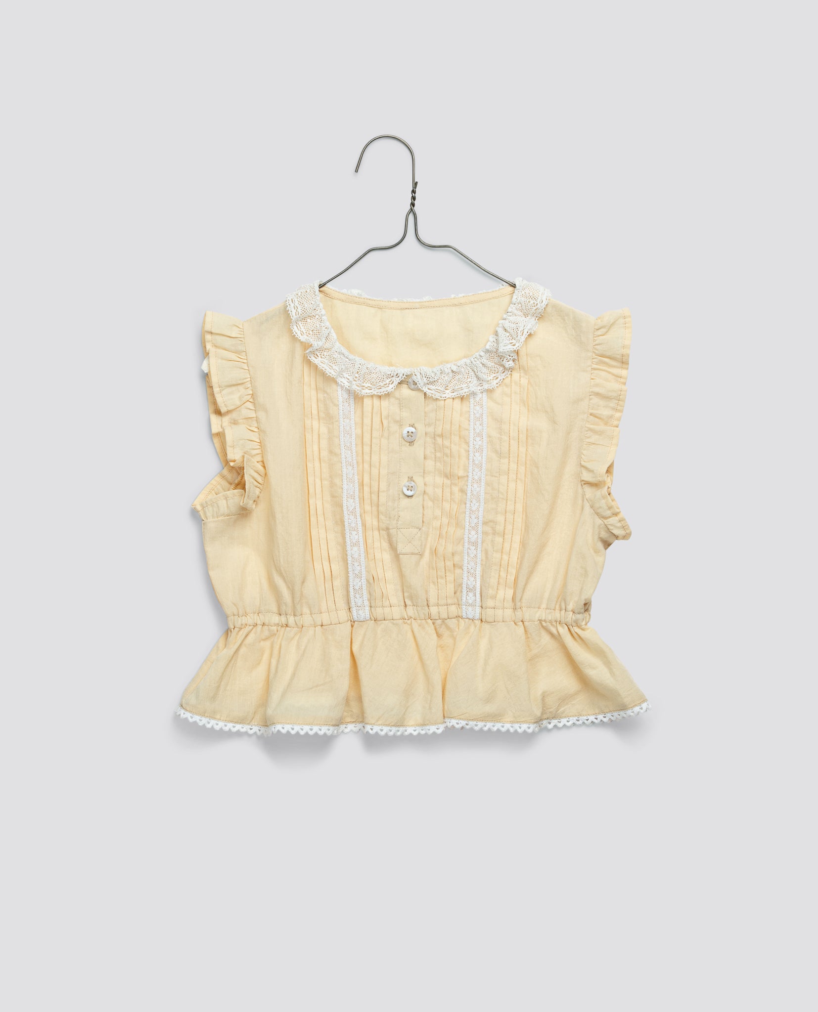 Butter yellow girls blouse made from organic cotton, featuring a vintage style with delicate lace trim and ruffled sleeves, designed for sustainable, ethical children's clothing.