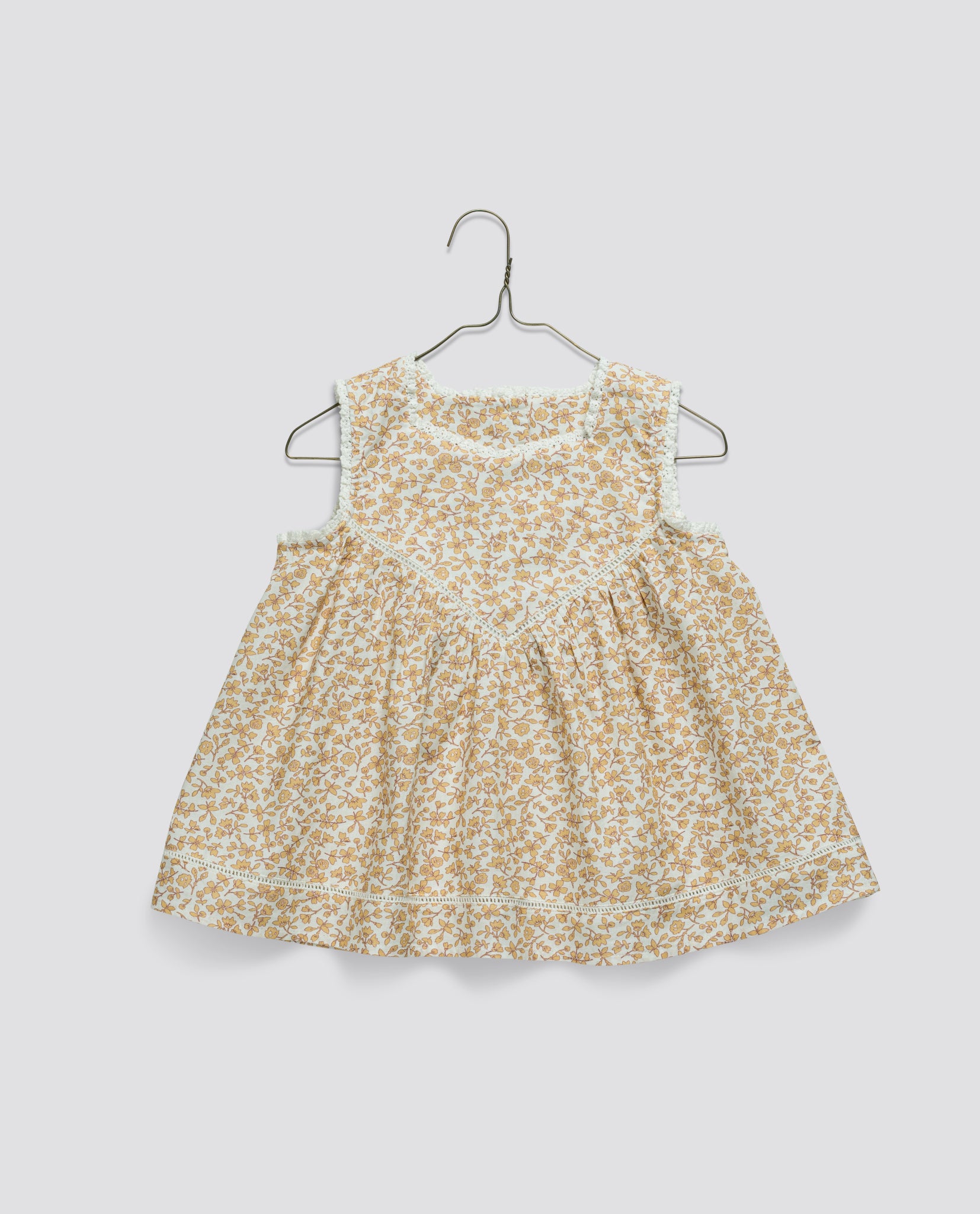 Sleeveless vintage-style girls top in soft natural cotton featuring a delicate yellow floral pattern, with a comfortable, loose fit perfect for childhood play.