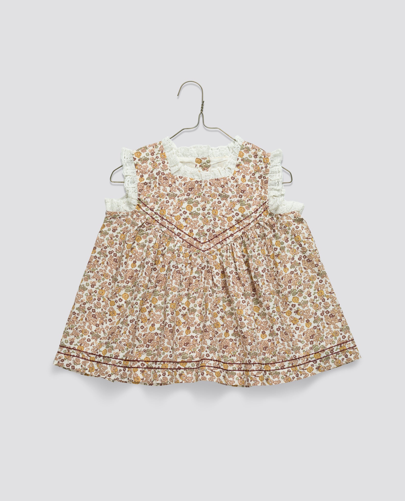 Vintage style girls blouse with a delicate floral pattern in natural tones, made from soft organic cotton, featuring ruffled sleeves and sustainable design.