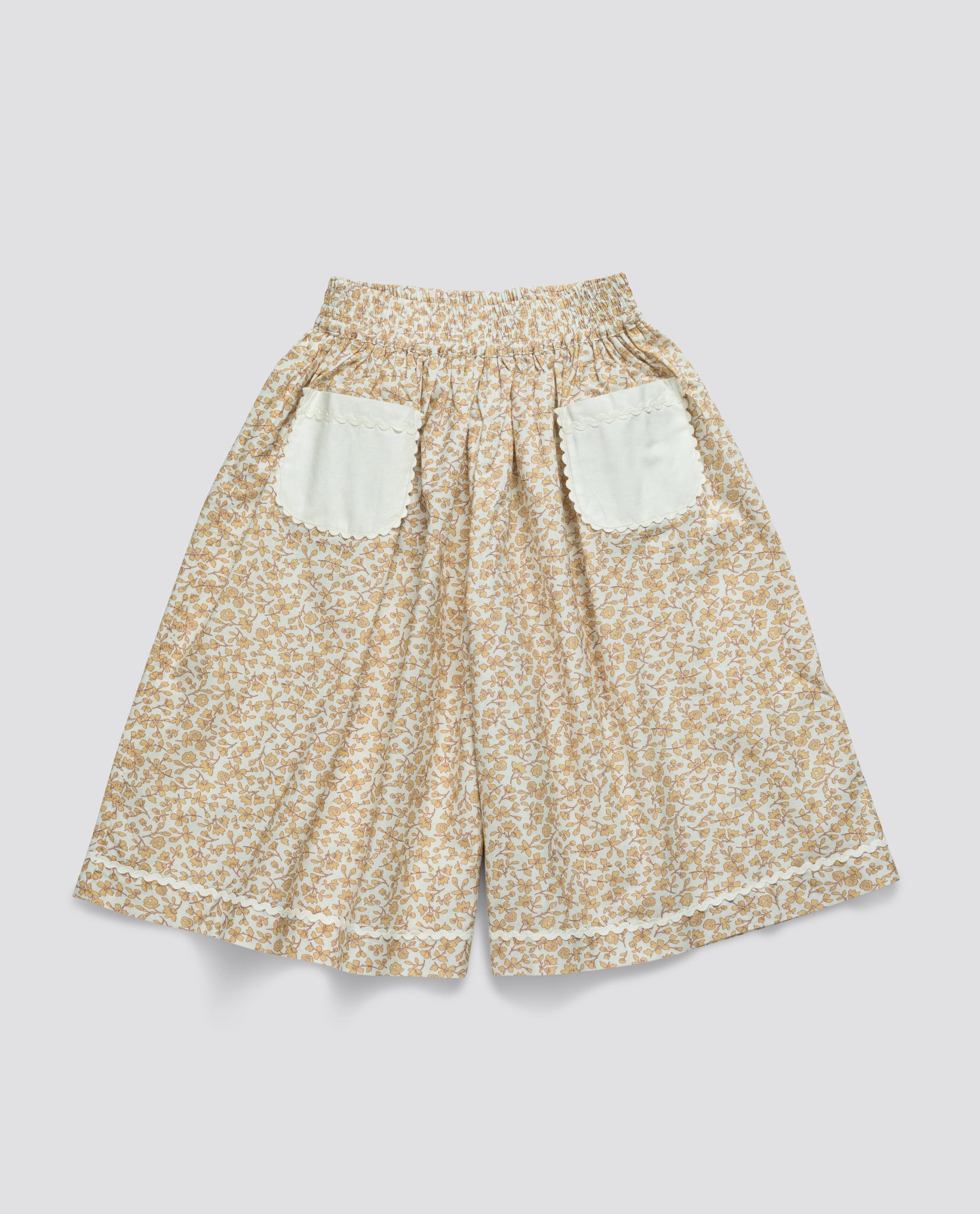 Light beige floral vintage-style culottes for girls made from organic cotton with elastic waist and white scalloped edge pockets, ethically crafted for comfort and style.