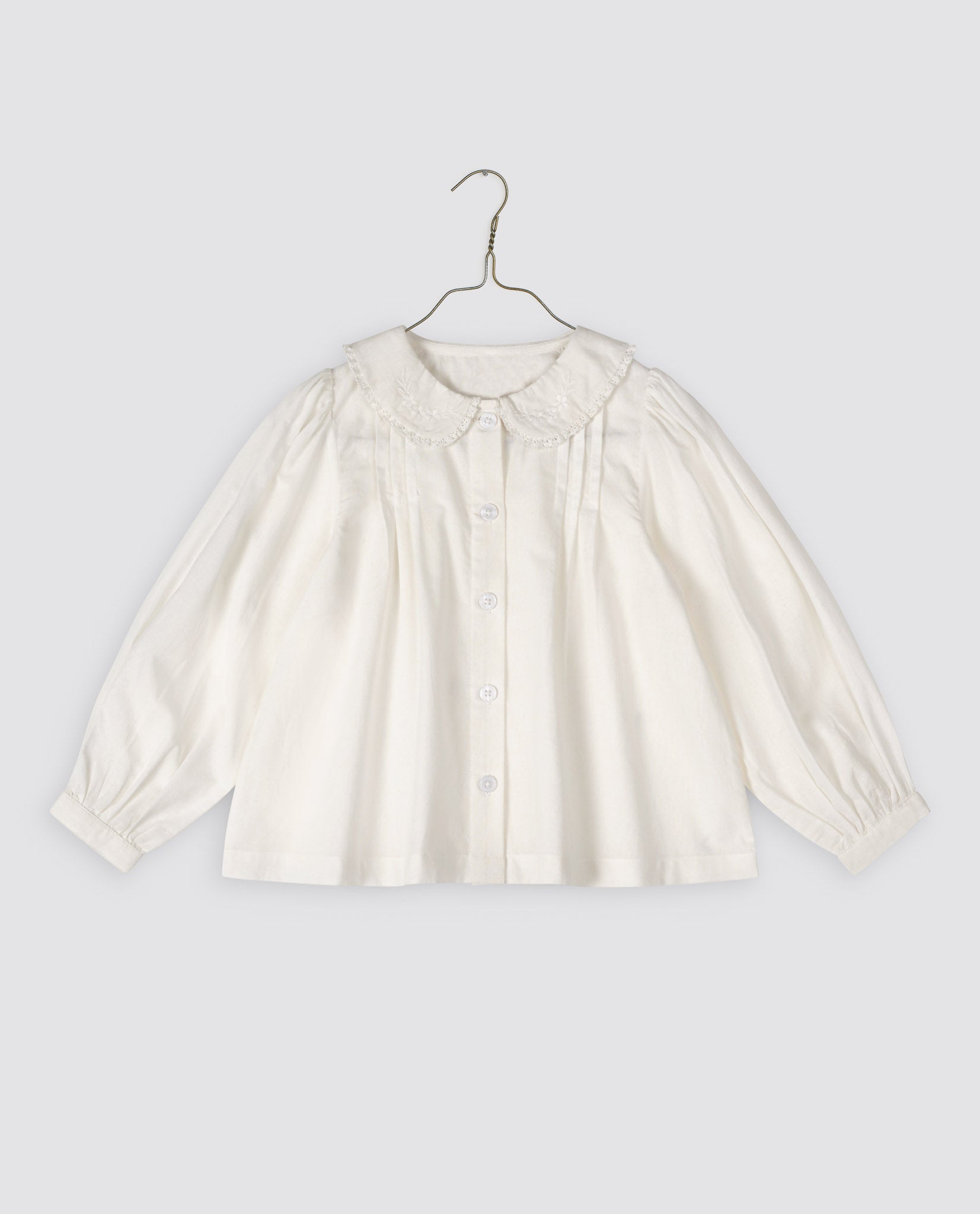 Off-white girls blouse made from organic cotton featuring a vintage-inspired embroidered collar and gentle pleats, designed with natural, sustainable materials for kids.
