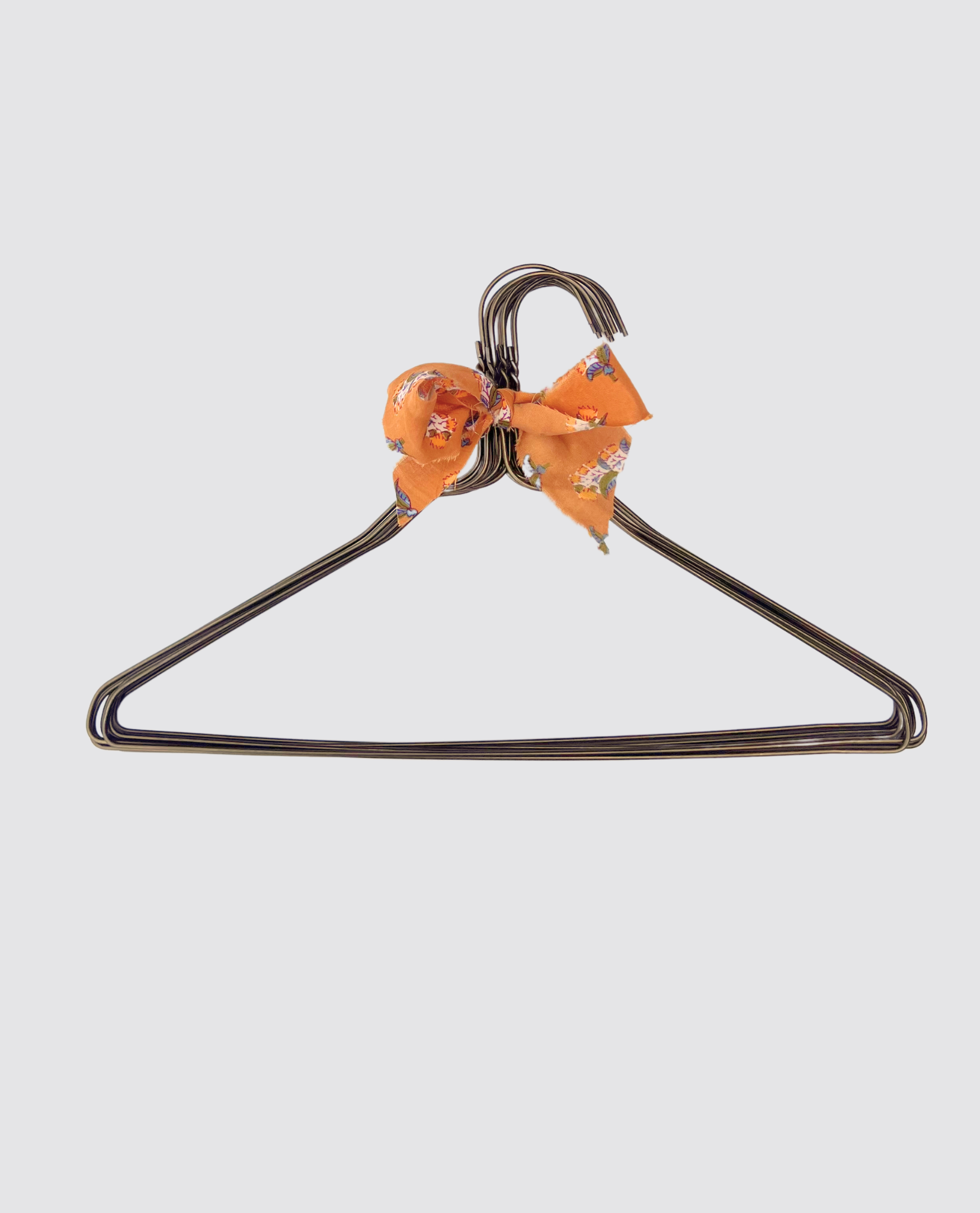 Gray metal children's hanger with a soft vintage-style orange fabric bow, designed to complement sustainable and ethically made kids clothing with a natural, timeless feel.