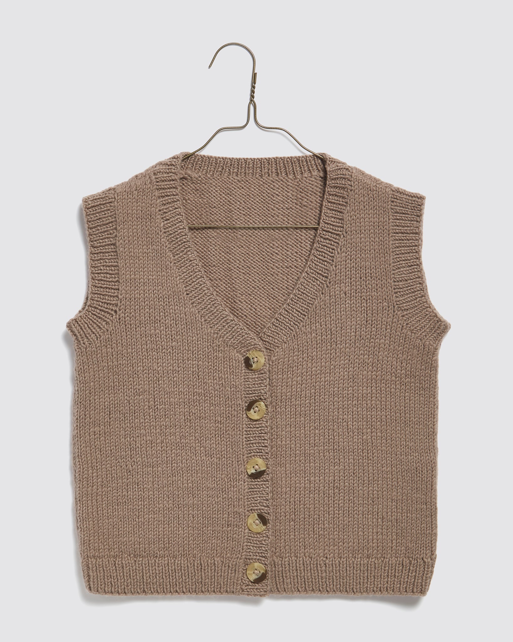 Hand-knitted beige merino wool vest for kids with a vintage, natural style, featuring wooden buttons, crafted with care from sustainable materials for ethical children's clothing.