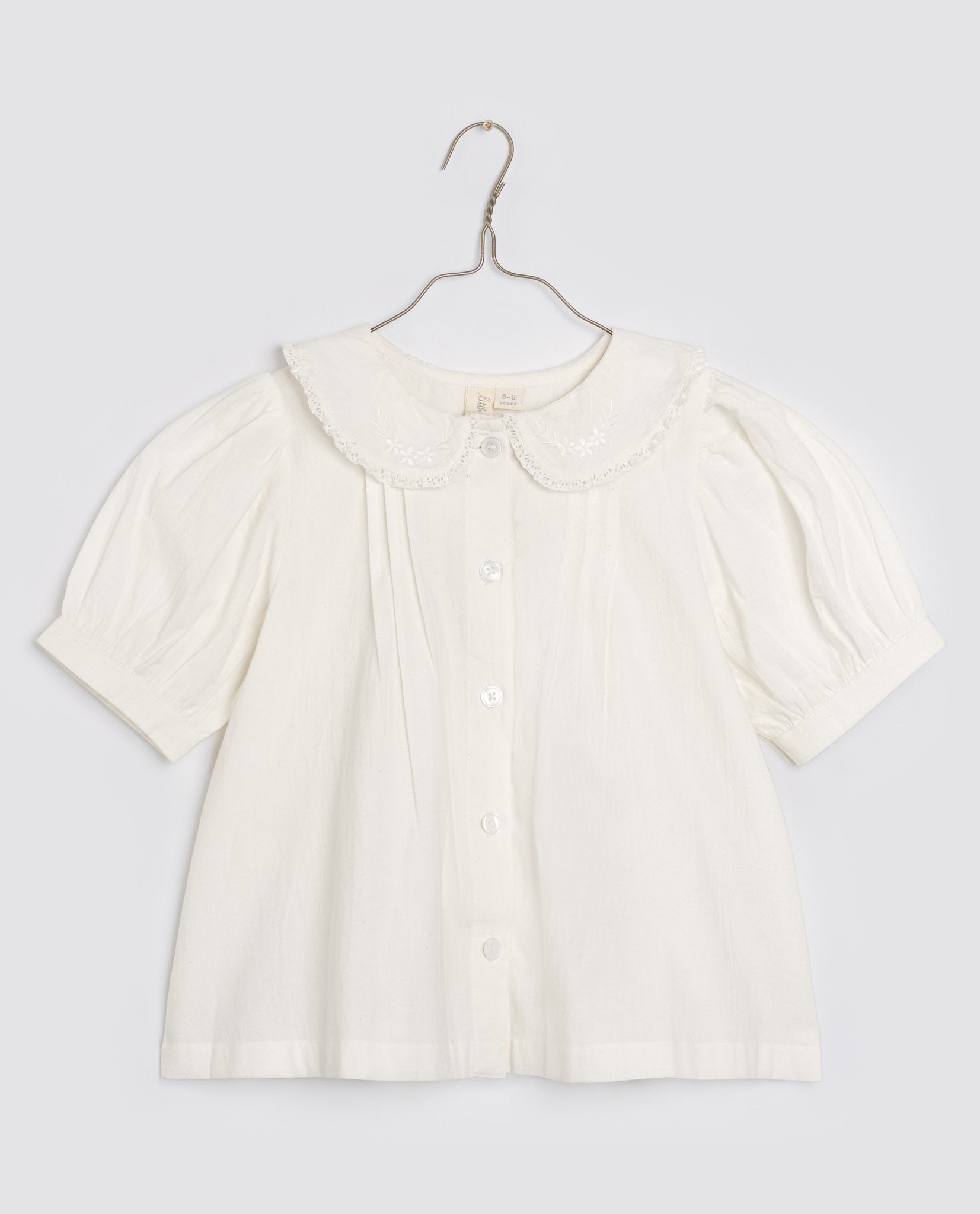 Off-white organic cotton girls blouse with vintage-style peter pan collar, delicate embroidery, and short puff sleeves, made sustainably for natural children's clothing.
