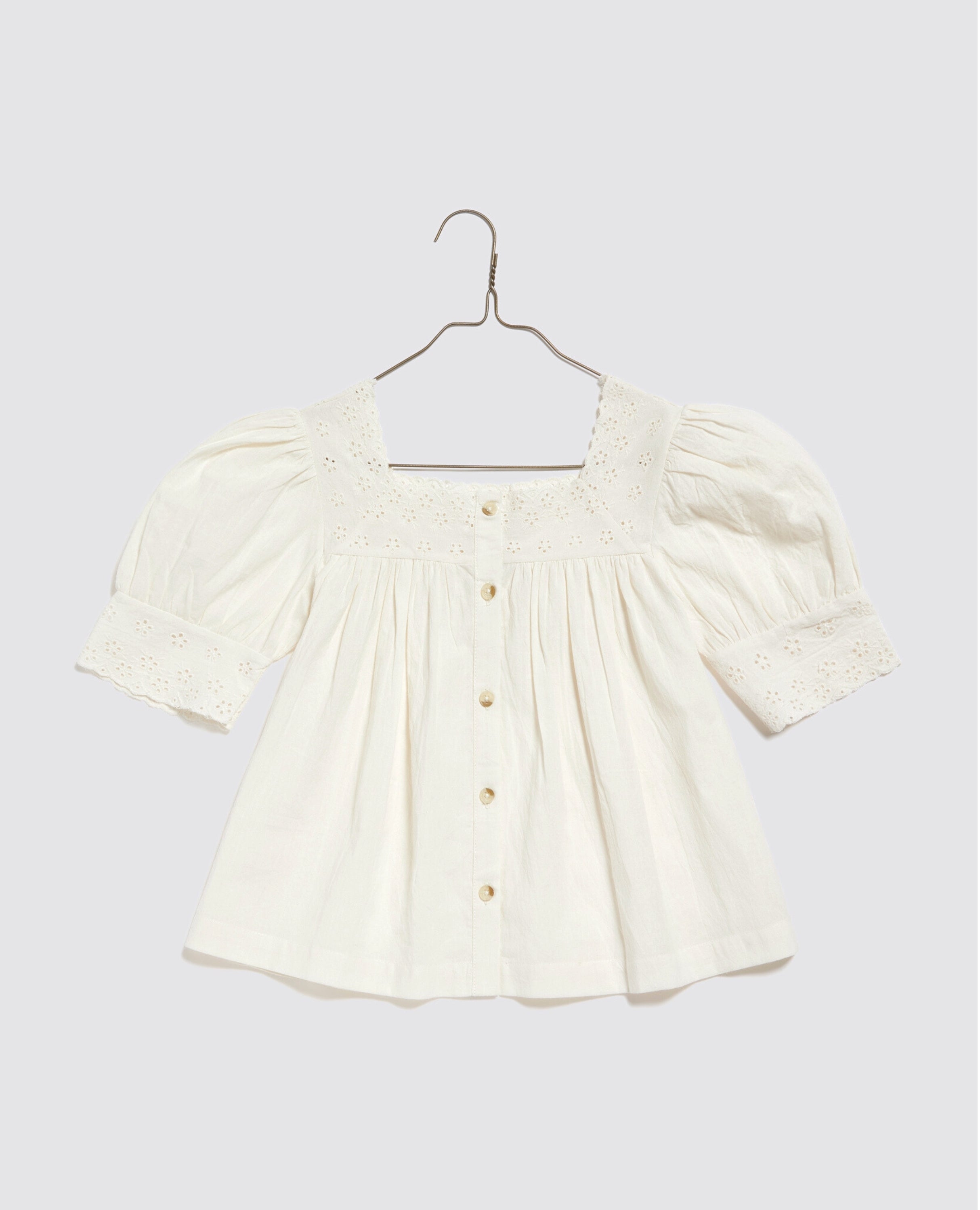 Off white girls blouse made from organic cotton with vintage-inspired puff sleeves and delicate eyelet embroidery, designed for ethical and sustainable children's clothing.