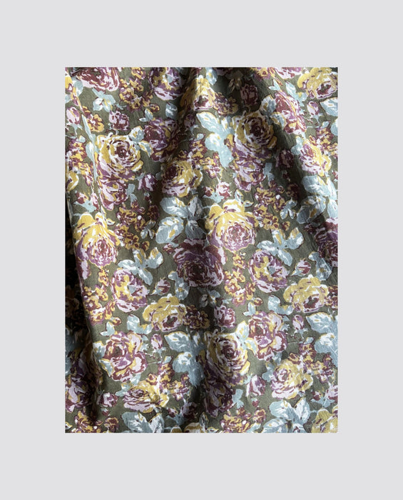 Close-up of organic cotton fabric with a vintage-inspired brown and floral wallpaper design, perfect for making sustainable, ethically crafted children's clothing.