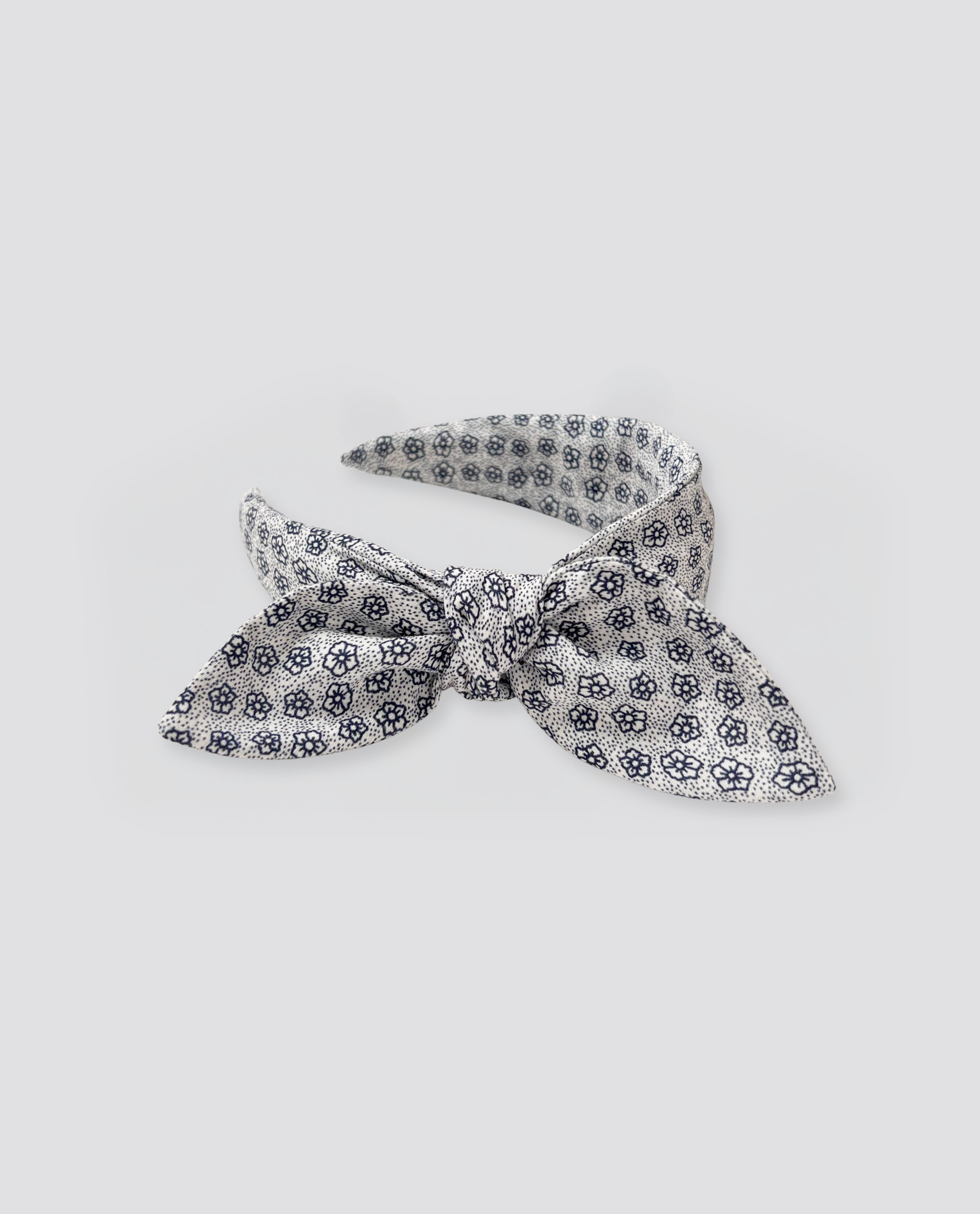 Vintage style wide hairband in soft natural fabric with delicate navy blue floral print, designed for children with an organic and ethical touch.