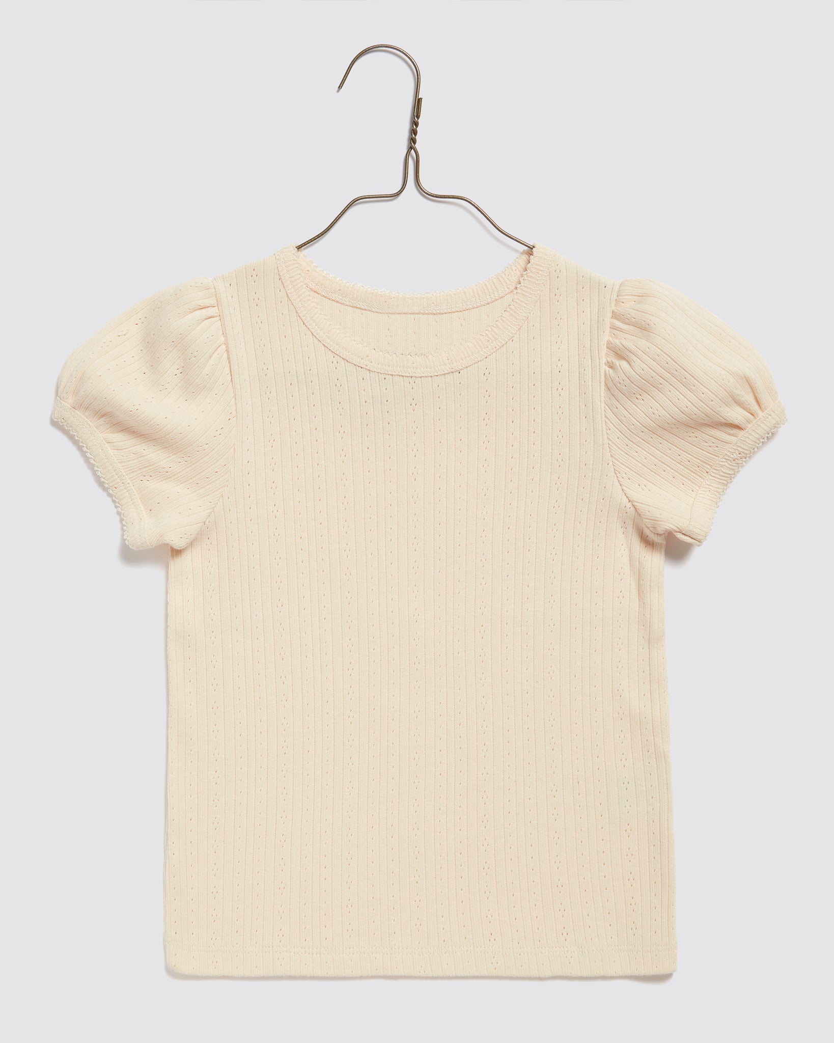 Cream-colored organic jersey cotton children's T-shirt with delicate pointelle texture and puff sleeves, designed with a vintage-inspired, sustainable style.