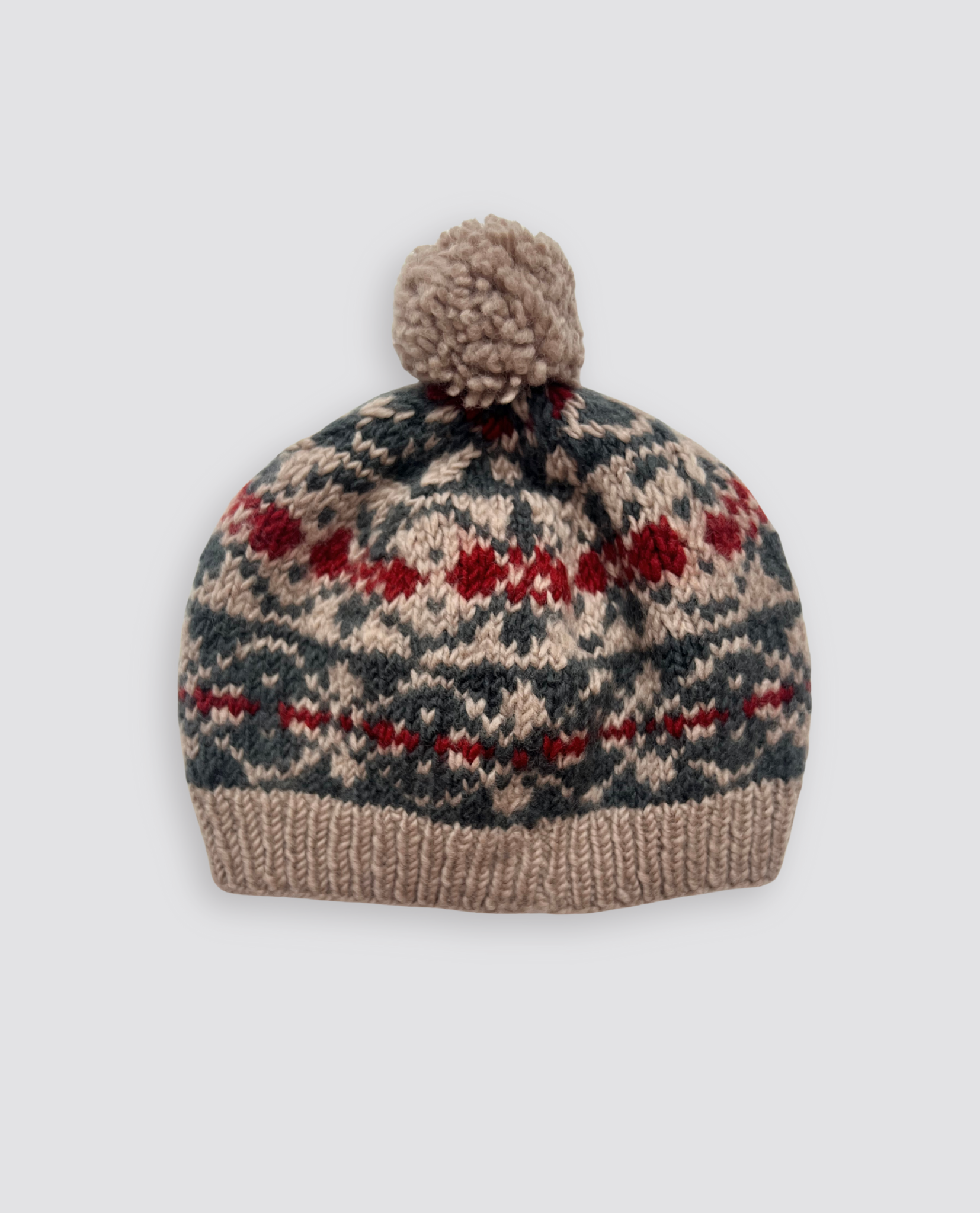 Hand-knitted kids bobble hat made from soft merino wool featuring a vintage-inspired multicolor Fairisle pattern, crafted with organic and sustainable care.