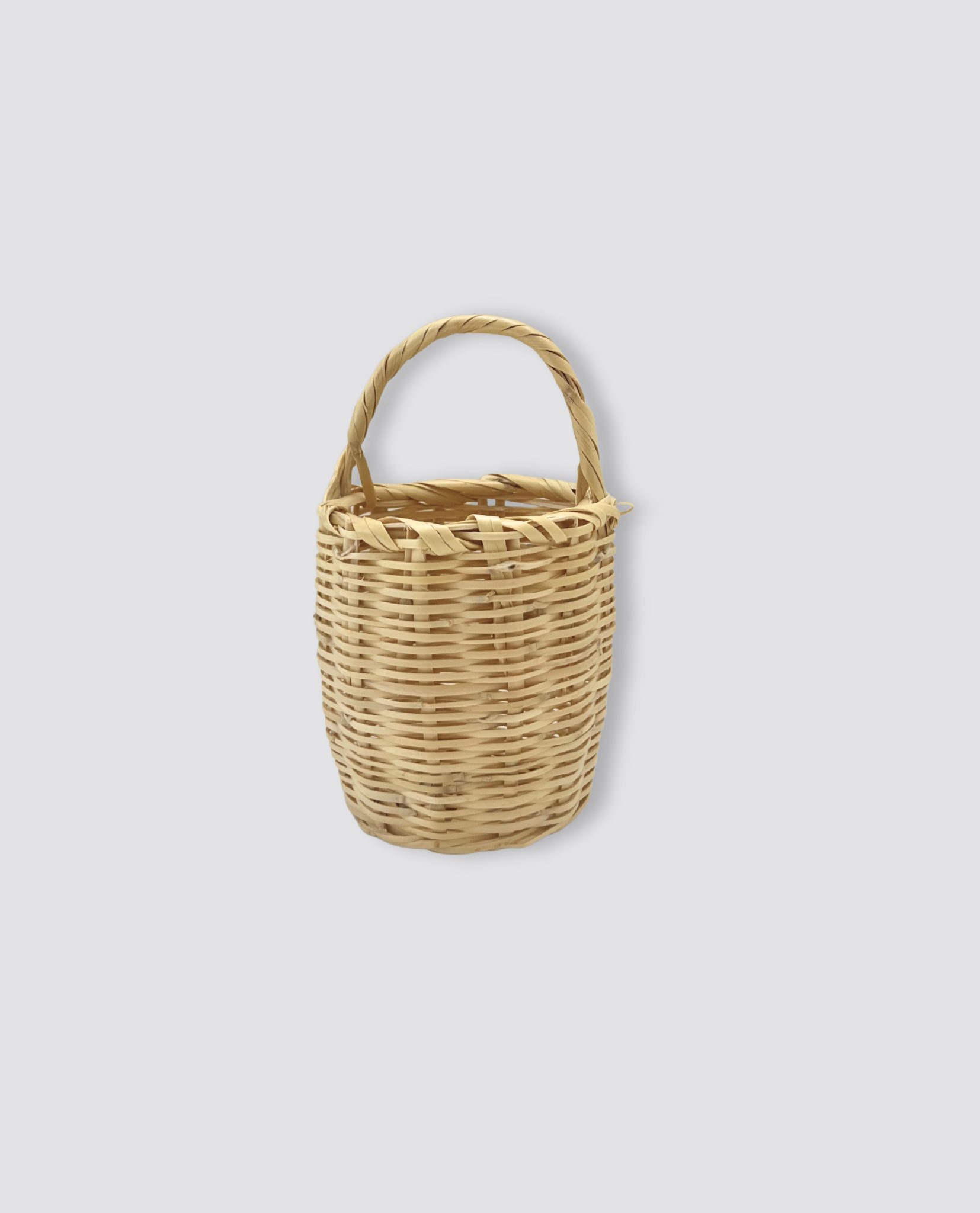 Small natural woven basket with a rounded handle, perfect for carrying childhood treasures in a slow, sustainable, and ethical vintage style.