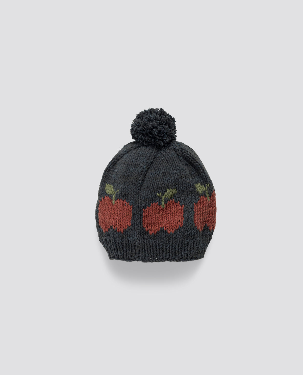 Hand-knitted bobble hat made with soft wool with charming apple pattern, reflecting vintage style and sustainable craftsmanship.