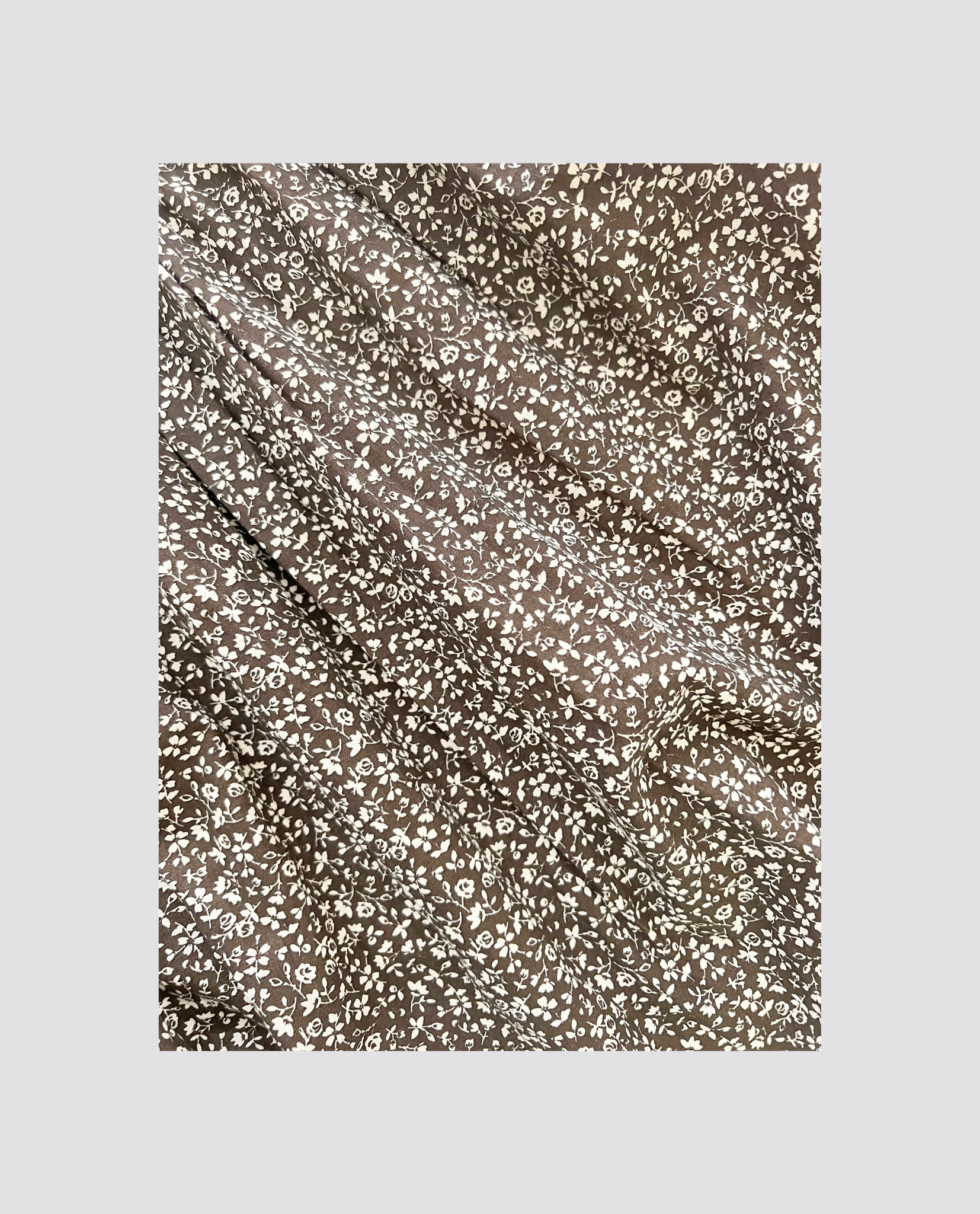 Organic brown cotton fabric with delicate white floral patterns, perfect for creating sustainable, vintage-style children's clothing with a natural, ethical touch.