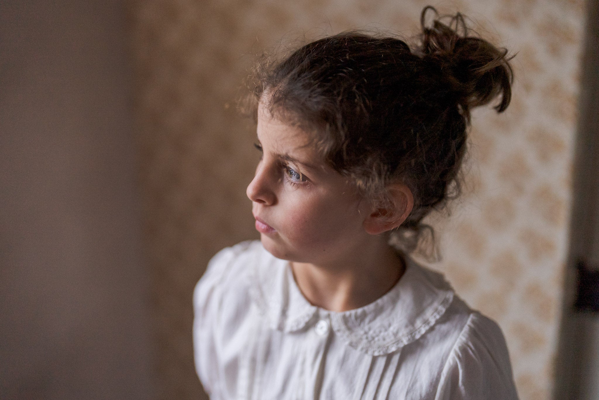 Young girl wearing an off-white cotton blouse with a vintage-style lace collar, showcasing sustainable, ethically made children's clothing with a natural, soft look.