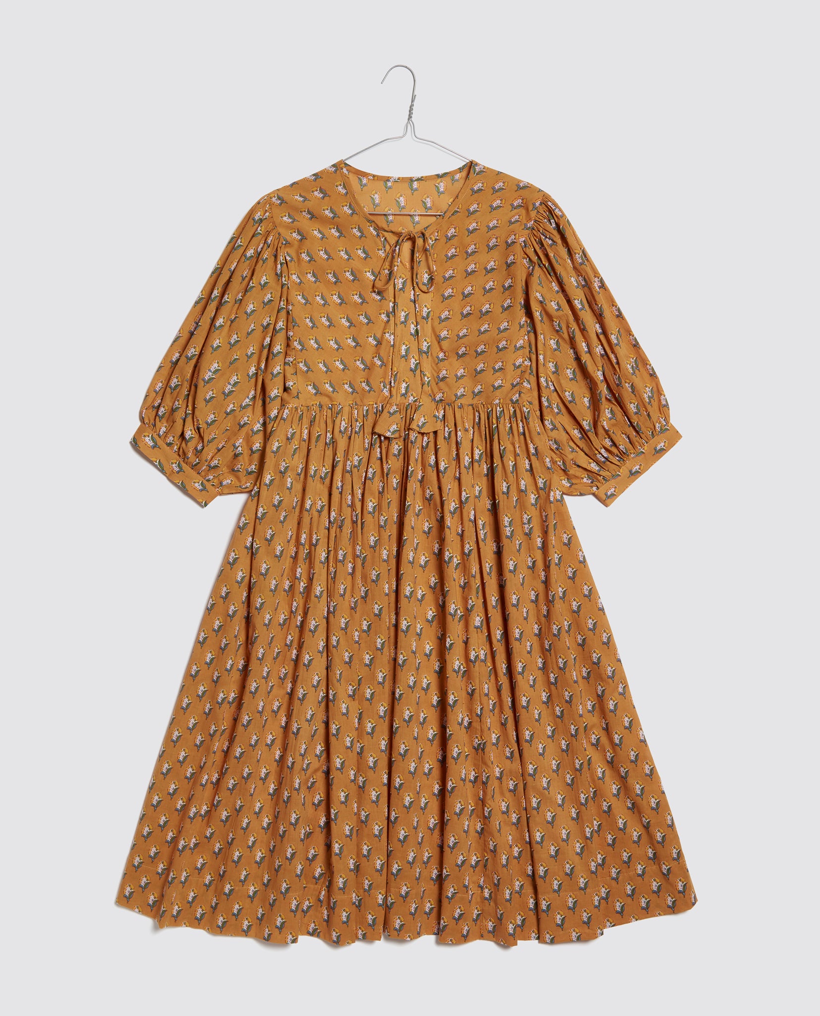 Vintage style girls dress in saffron yellow with delicate floral print, made from organic cotton with puffed sleeves and a tie neckline for a classic look.