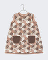 A-line girl's dress in printed patchwork design fabric. Brown, pink and white coloured floral print with contrasting patch pockets and ric-rac trim. 