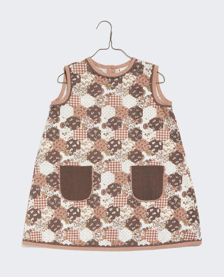 A-line girl's dress in printed patchwork design fabric. Brown, pink and white coloured floral print with contrasting patch pockets and ric-rac trim. 