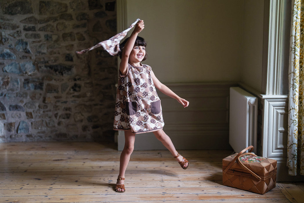 Dancing in a vintage style A-line girl's dress in printed patchwork design fabric. Short length summer dress, sleeveless with pockets with ric-rac trim. 