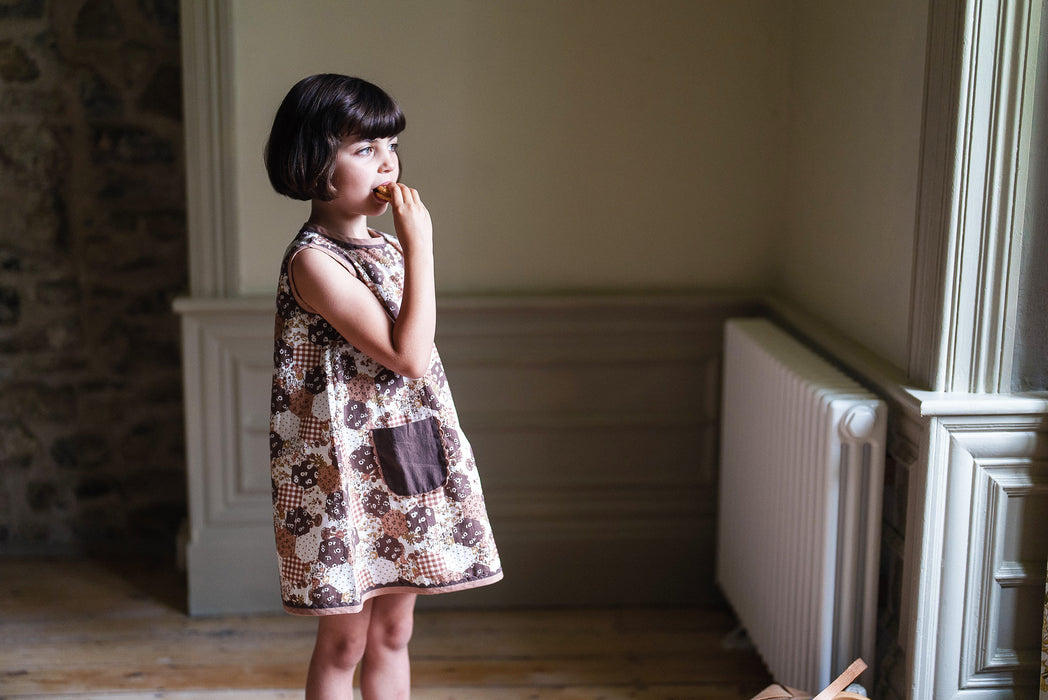 Retro inspired girl's summer dress. Sleeveless design with contrasting trim and patch pockets. Made from printed floral patchwork on organic cotton.