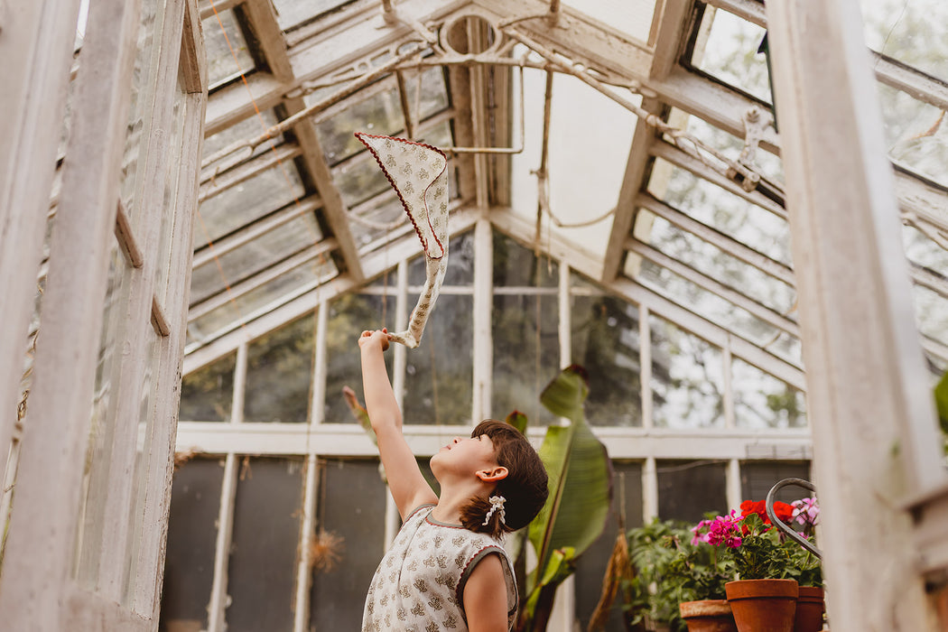 Floral scarf accessory being playfully thrown into the air. 