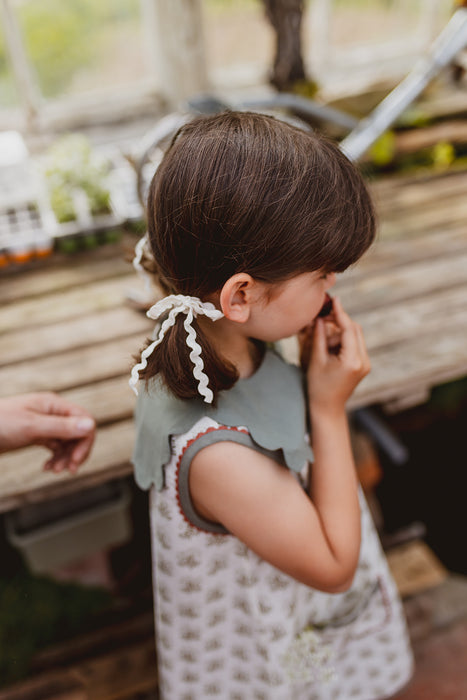 Model wears ric-rac trim bows in the her hair with a pretty green scalloped collar, and retro inspired floral summer dress with ric-rac trim.